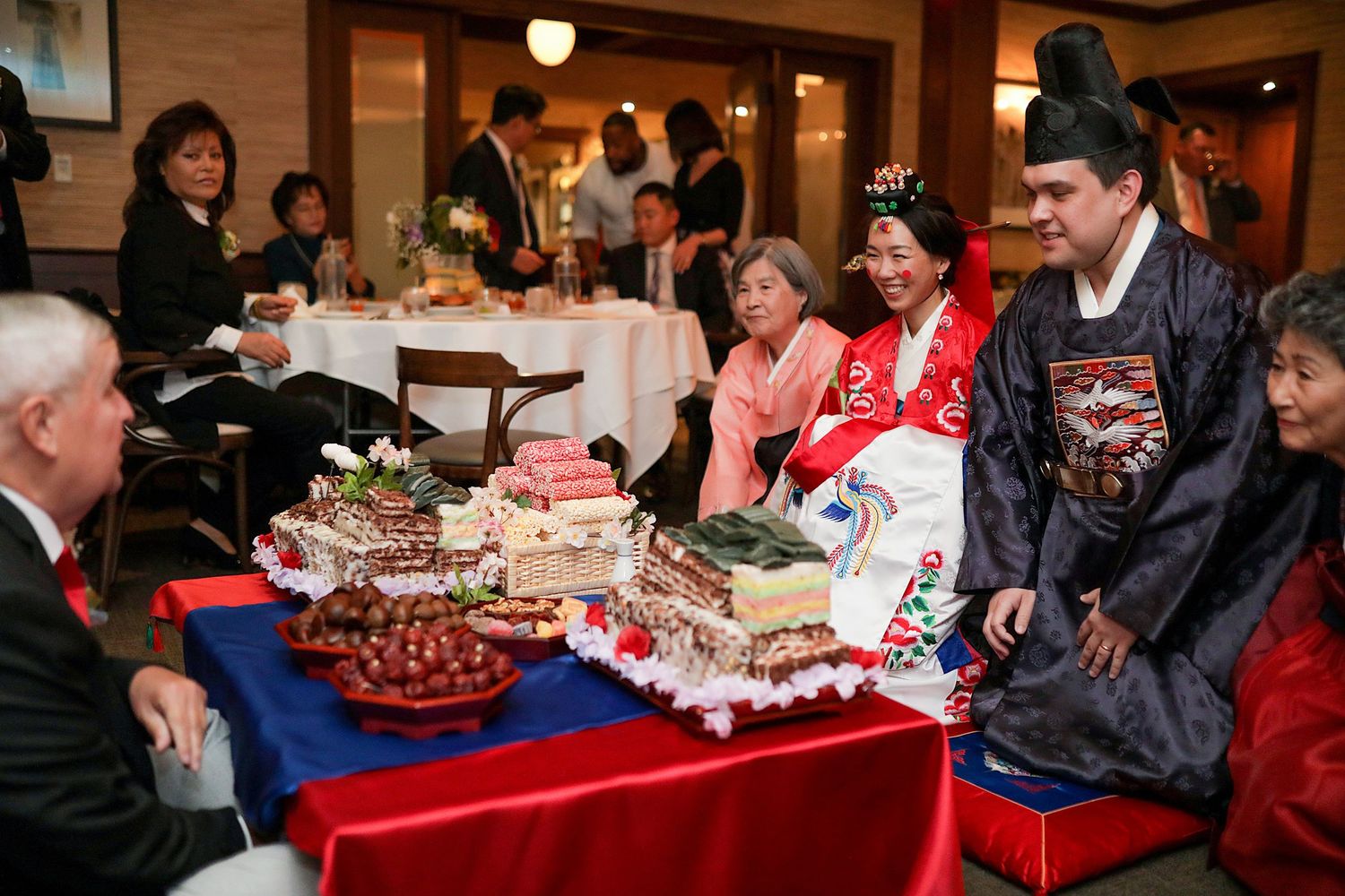 People gathered around tables with festive food and desserts at a holiday party or celebration event.