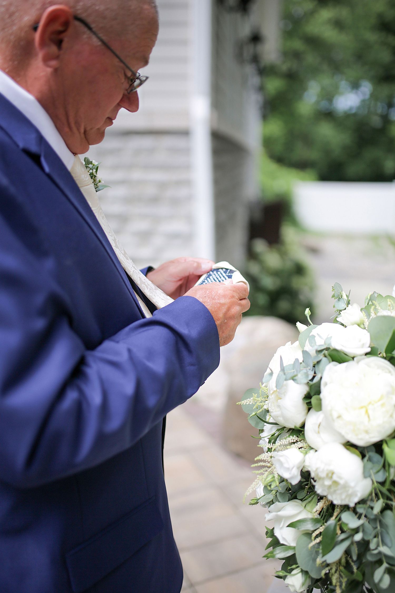 Close-up shots of guest reading wedding program next to white floral arrangements.