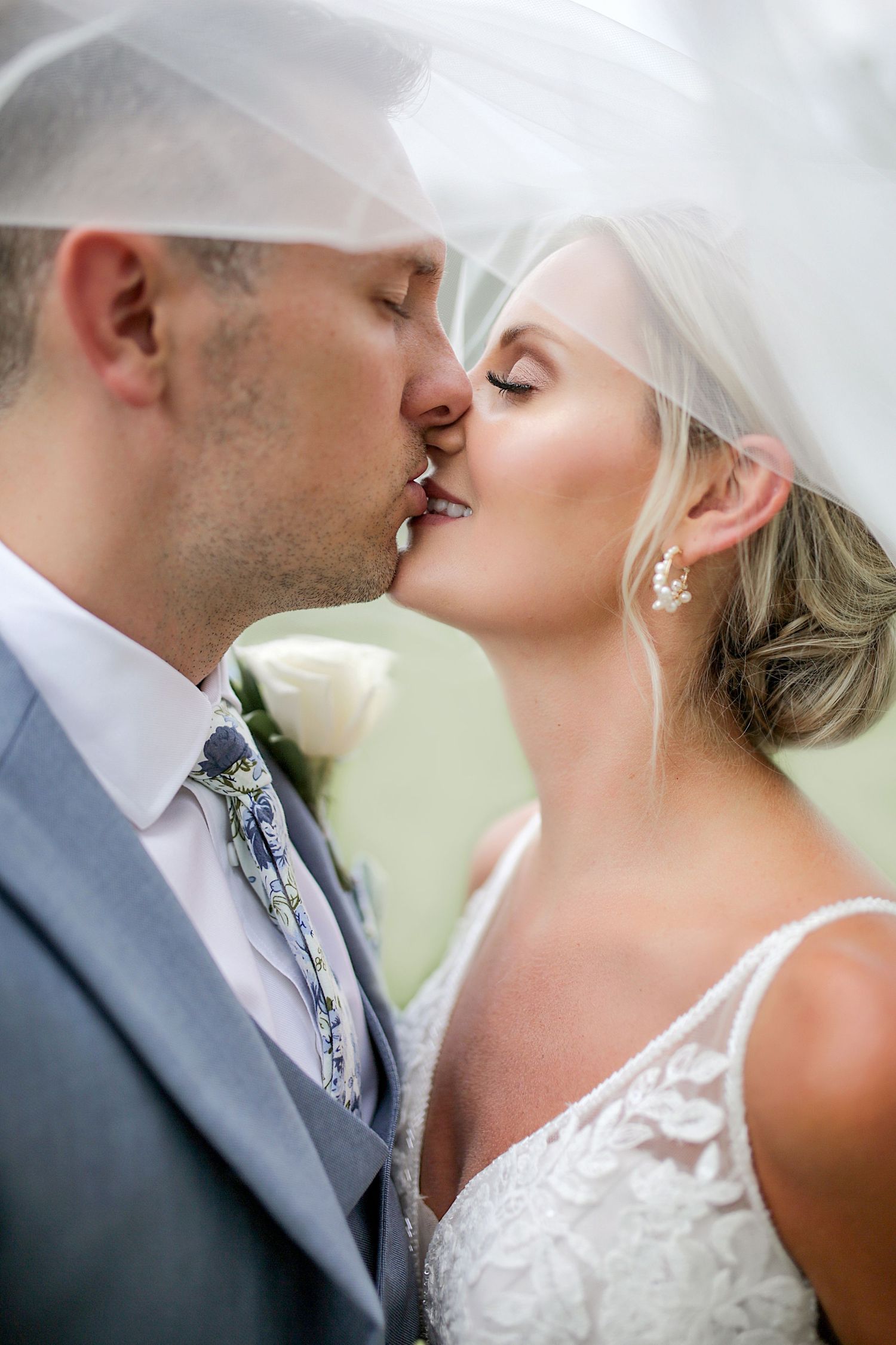 Intimate close-up wedding portrait with flowing veil in natural lighting.