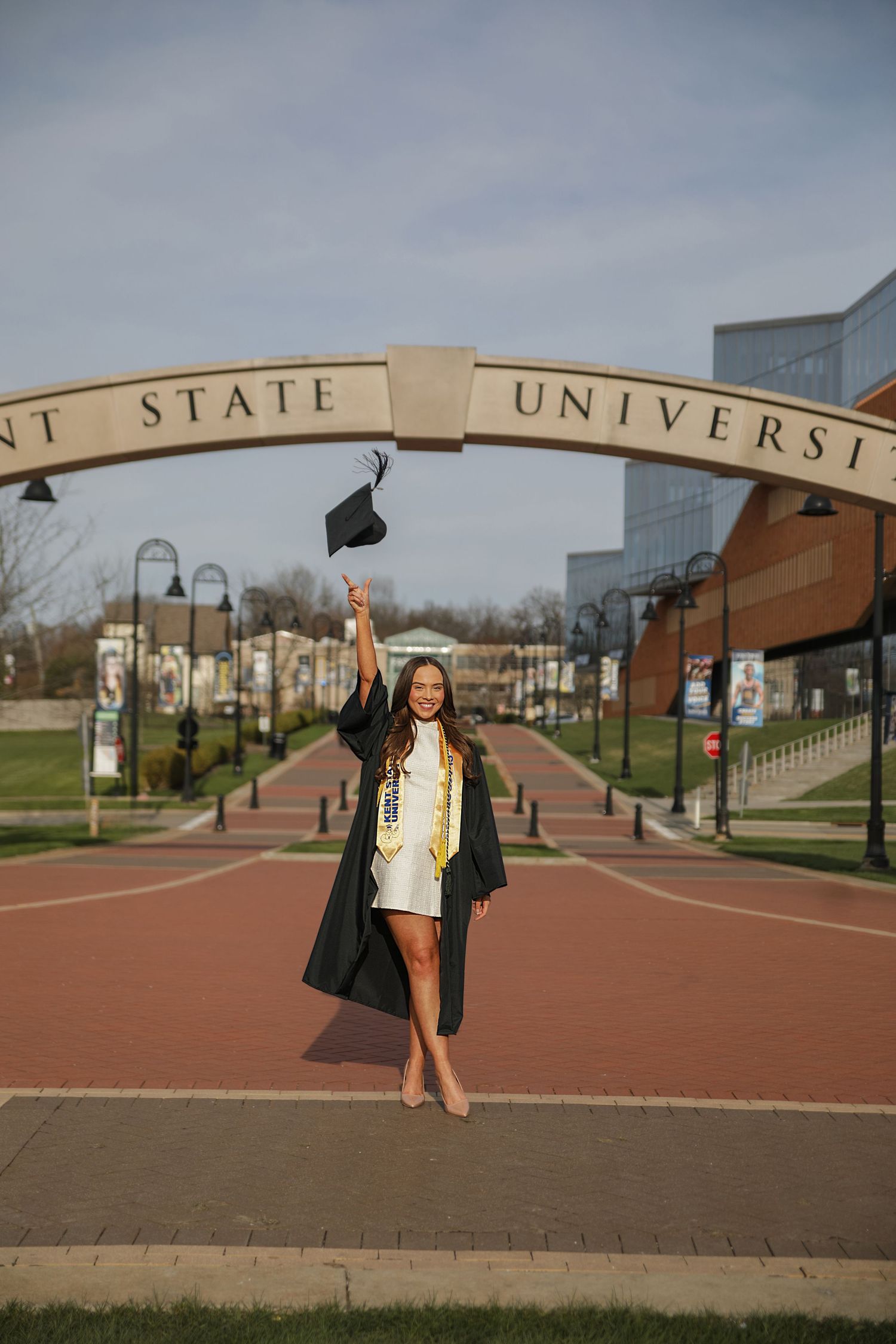A series of graduation photos showing a graduate in black cap and gown posing on a brick walkway at State University.