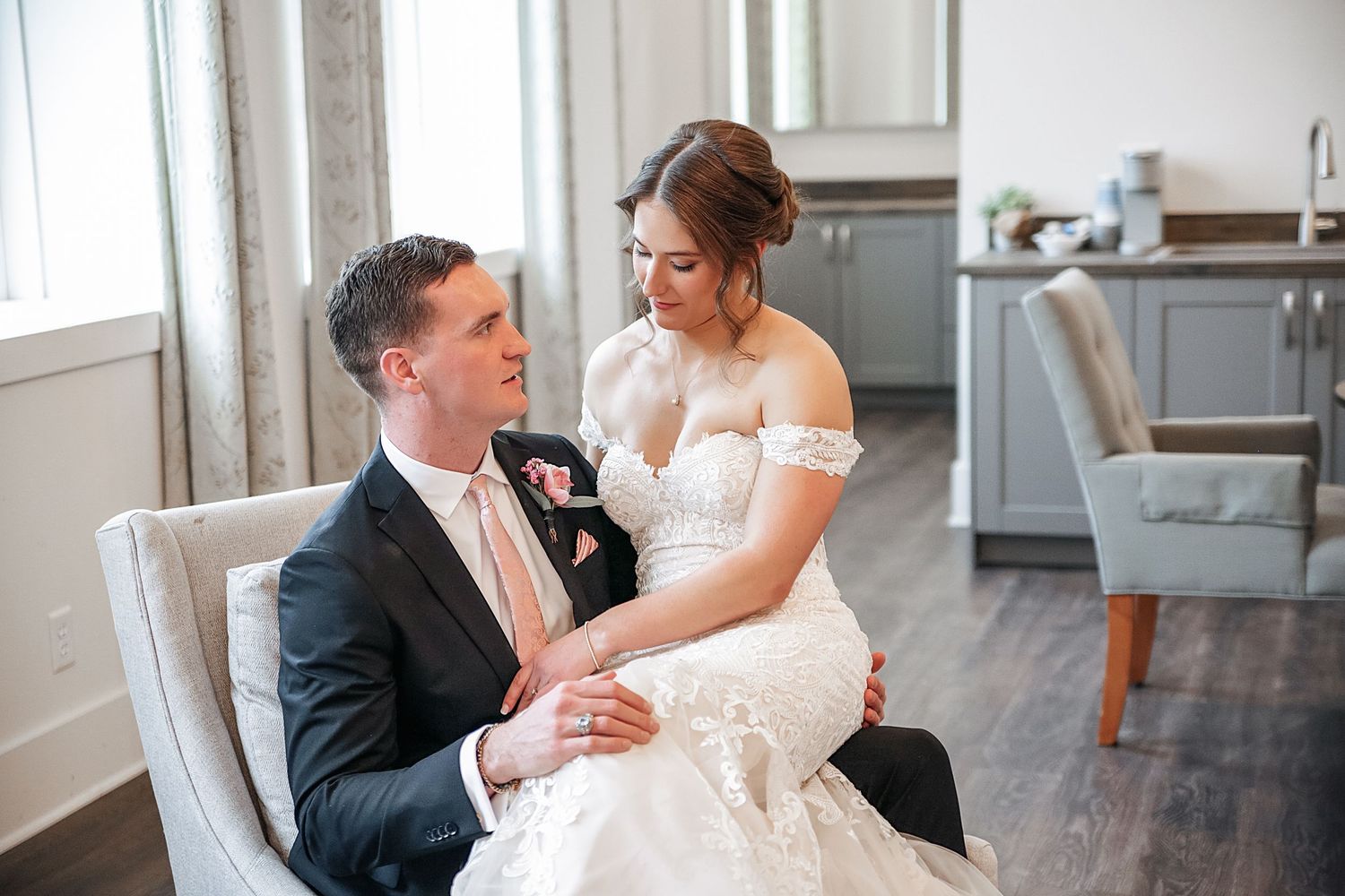 A bride and groom share an intimate moment while seated together in an elegant indoor setting.