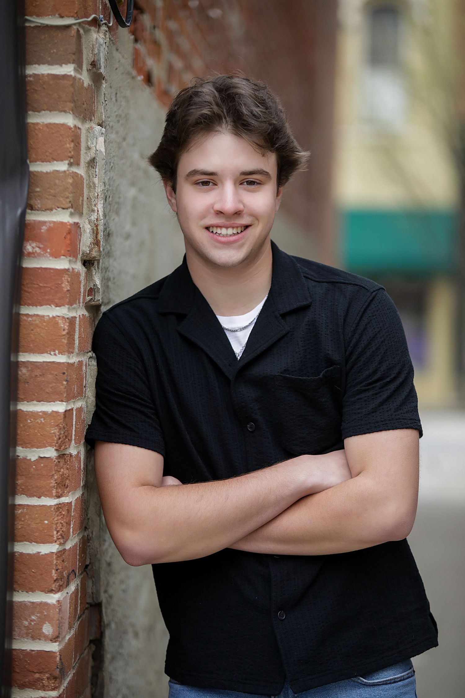 Portrait photo series showing someone in a black shirt leaning against a brick wall in different poses.