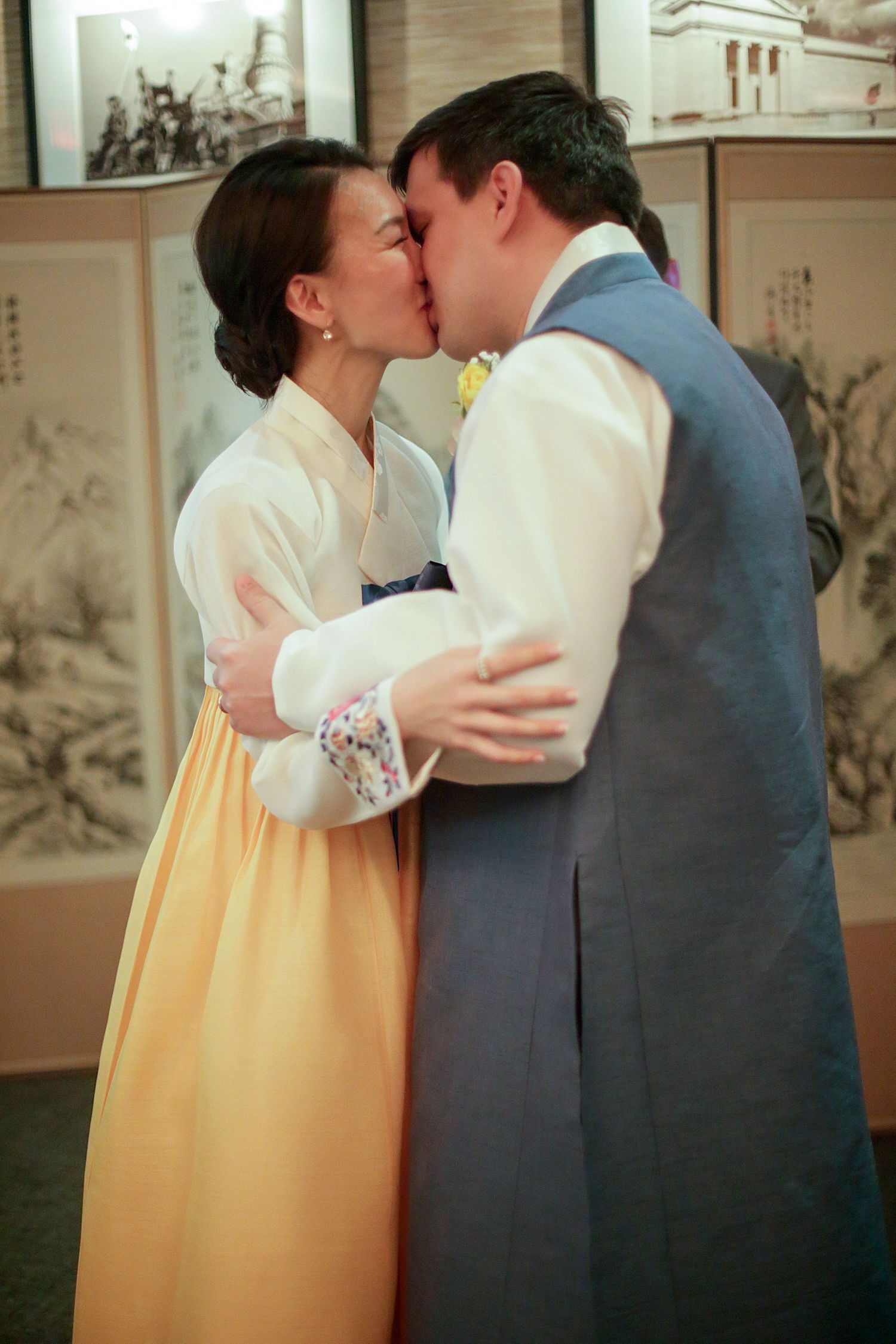A romantic scene shows a tender kiss shared between two people in period costumes with an Asian backdrop of art panels.