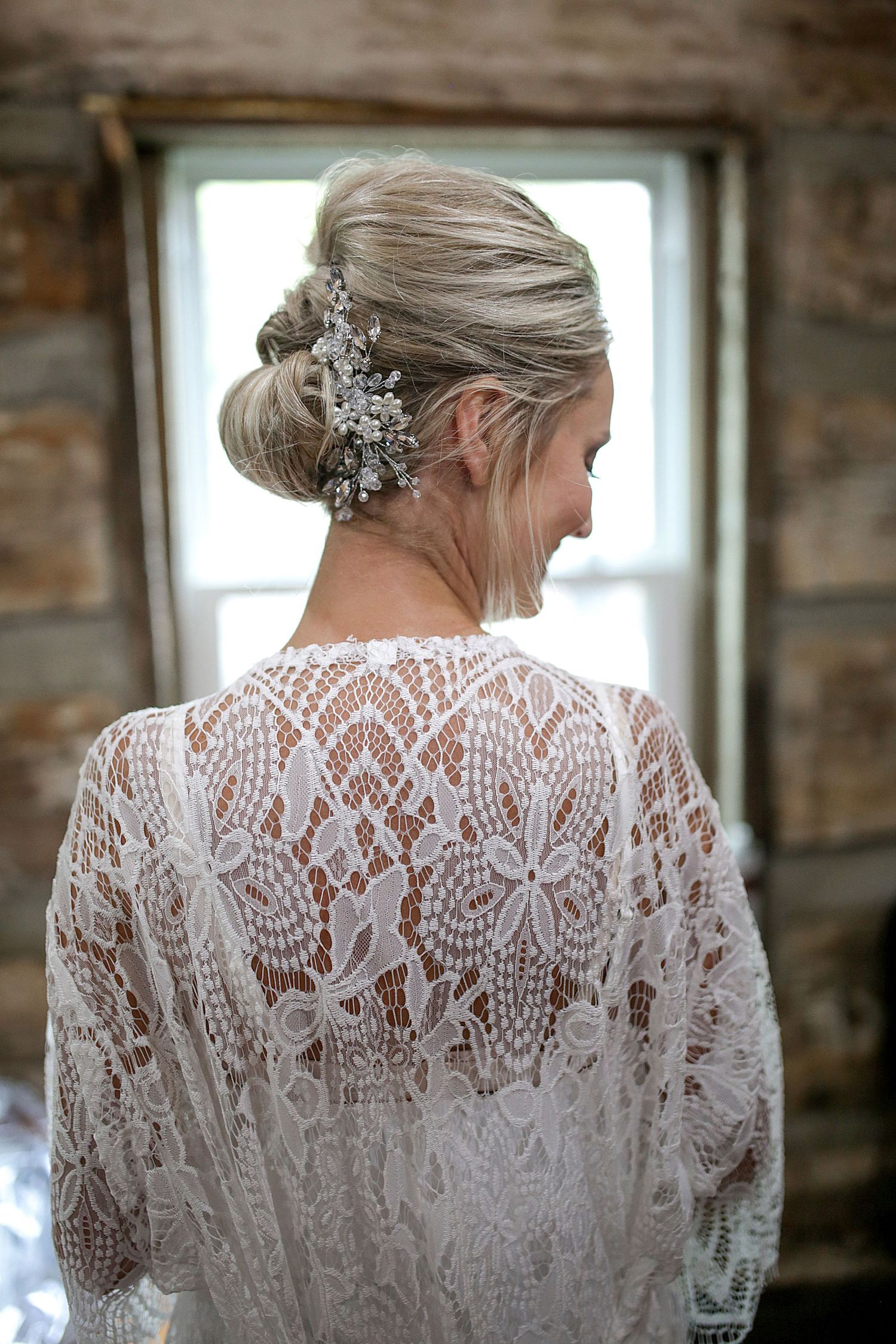 Detailed back view of bridal lace robe and elegant updo with crystal hair accessories.