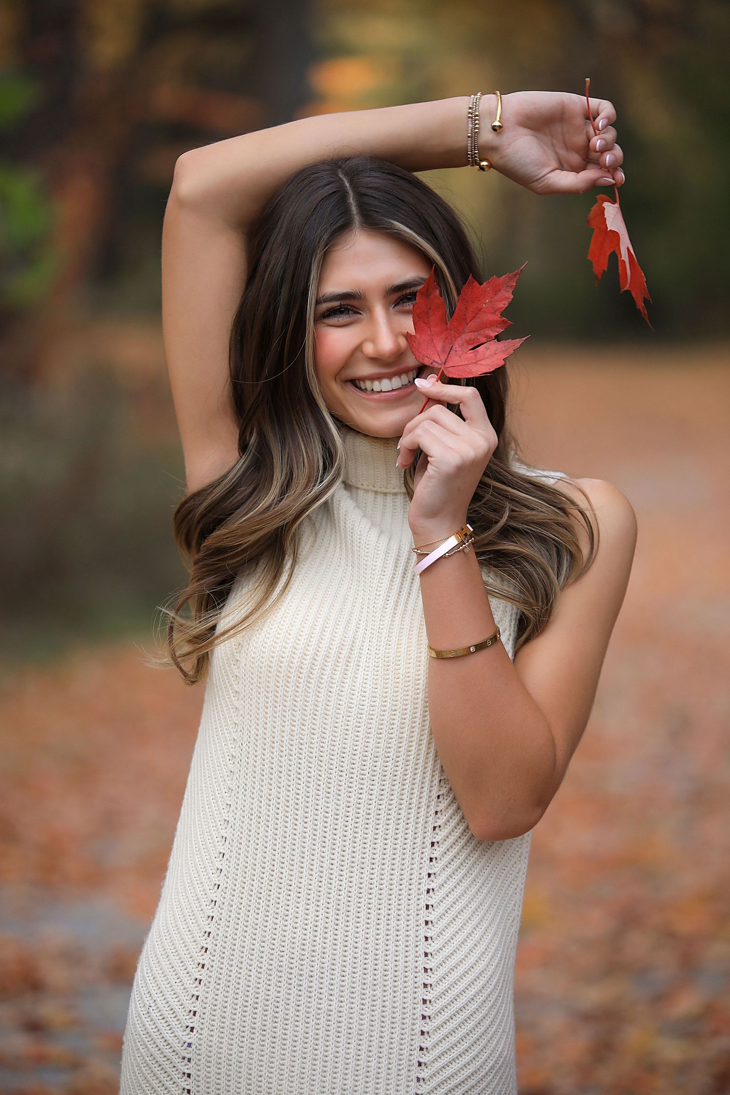 A playful fall photoshoot featuring a knit sweater and red maple leaf against an autumn background. Senior Photography Chagrin Falls Oh