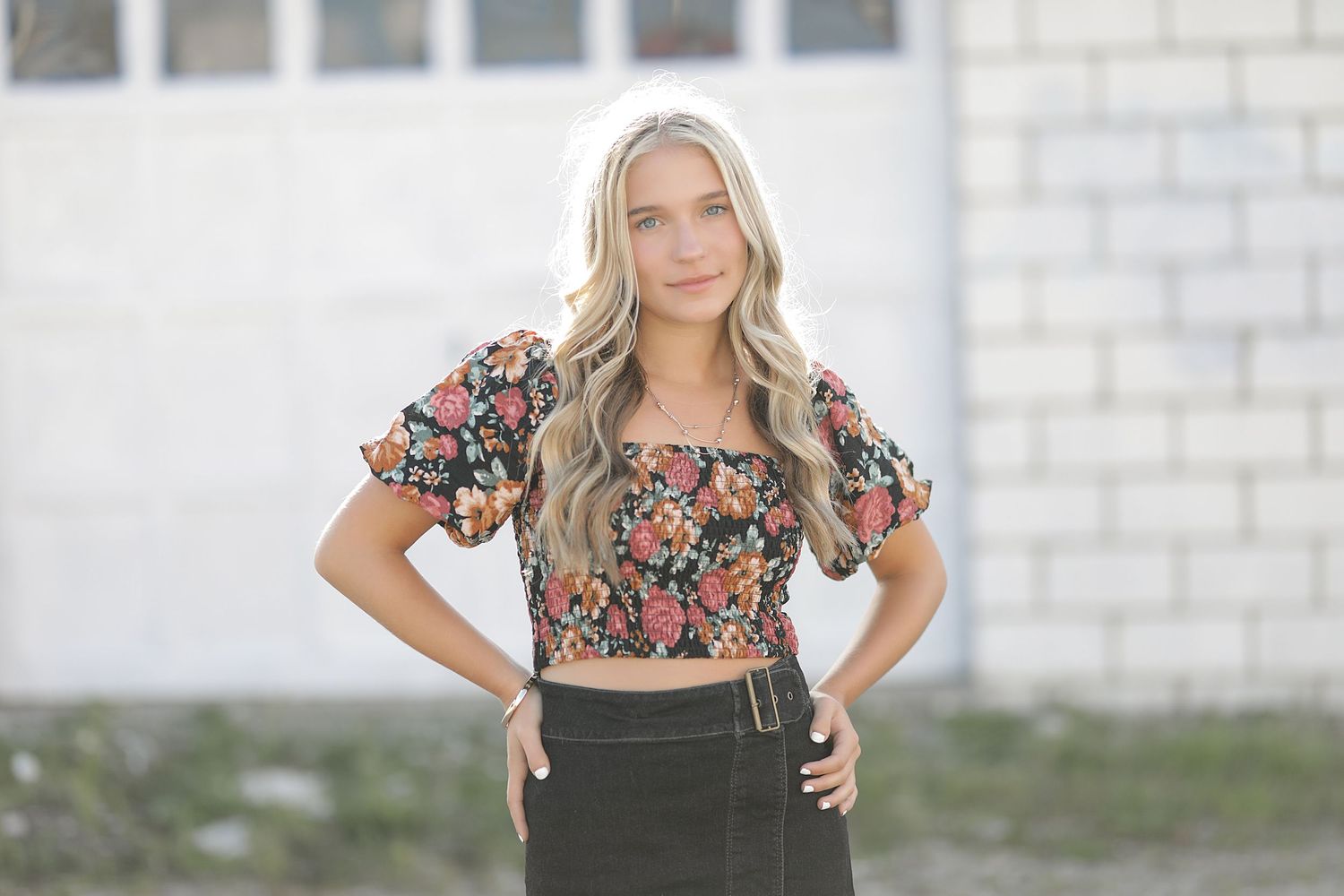Woman wearing floral print corset top against white brick wall in portrait photo series.