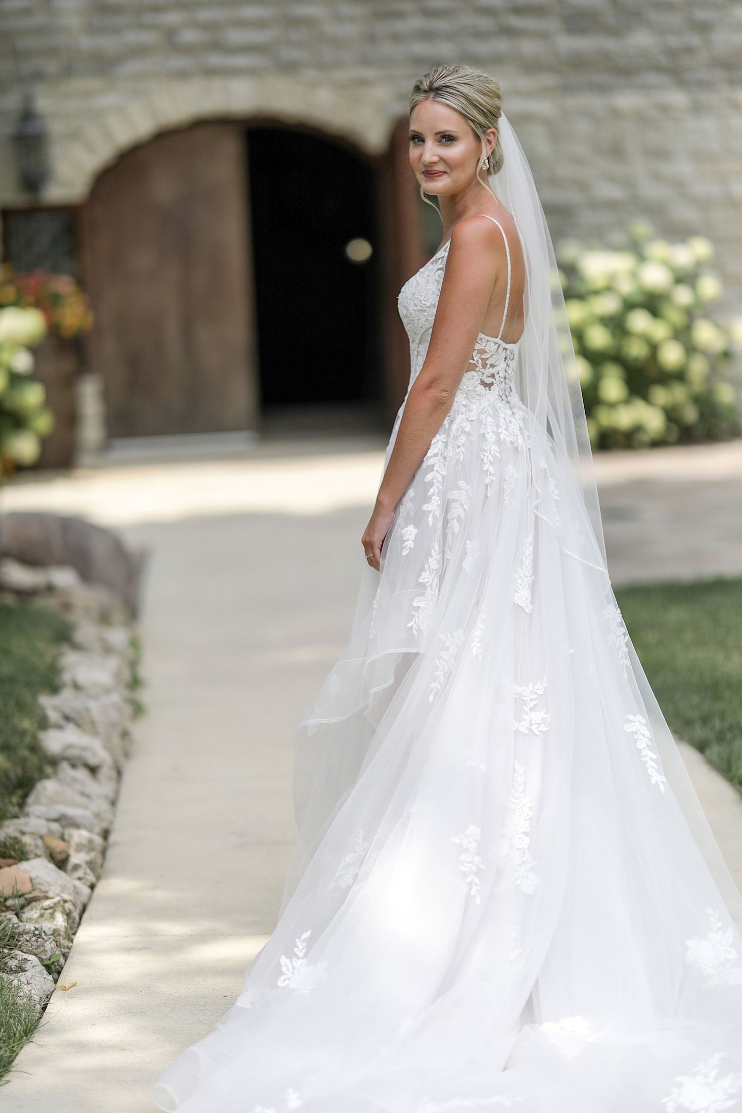 Elegant white wedding dress with flowing train and lace details captured in a series of outdoor bridal portraits.