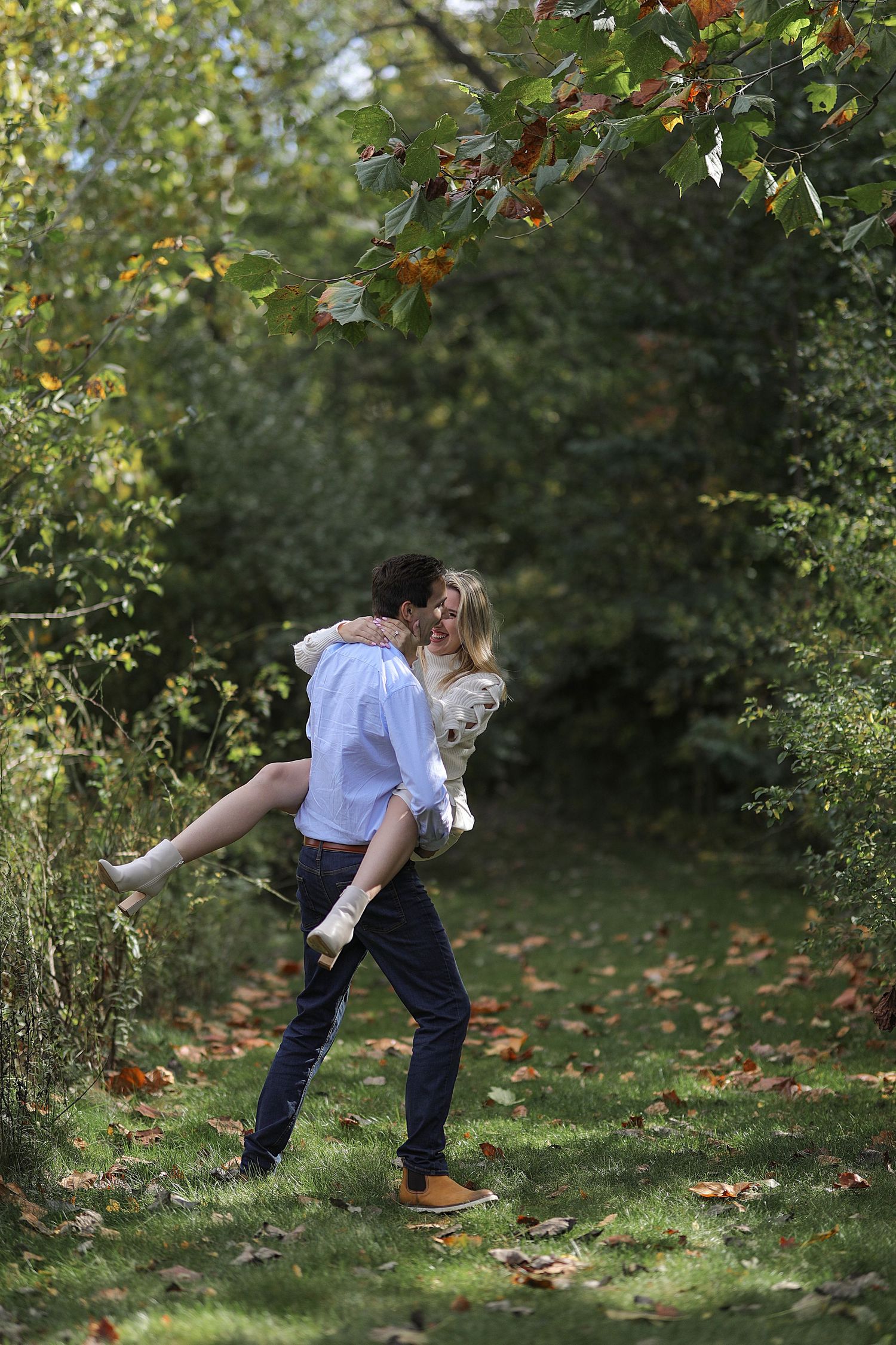 A romantic autumn scene in a wooded garden path with fallen leaves on the ground.
