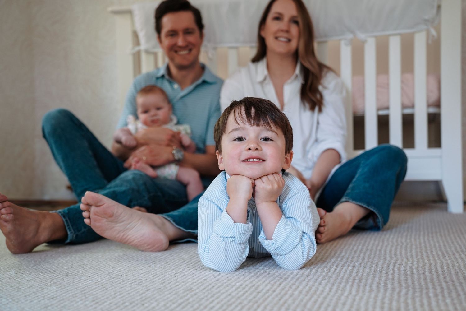A happy family lounging together on white bedding for casual lifestyle photography.