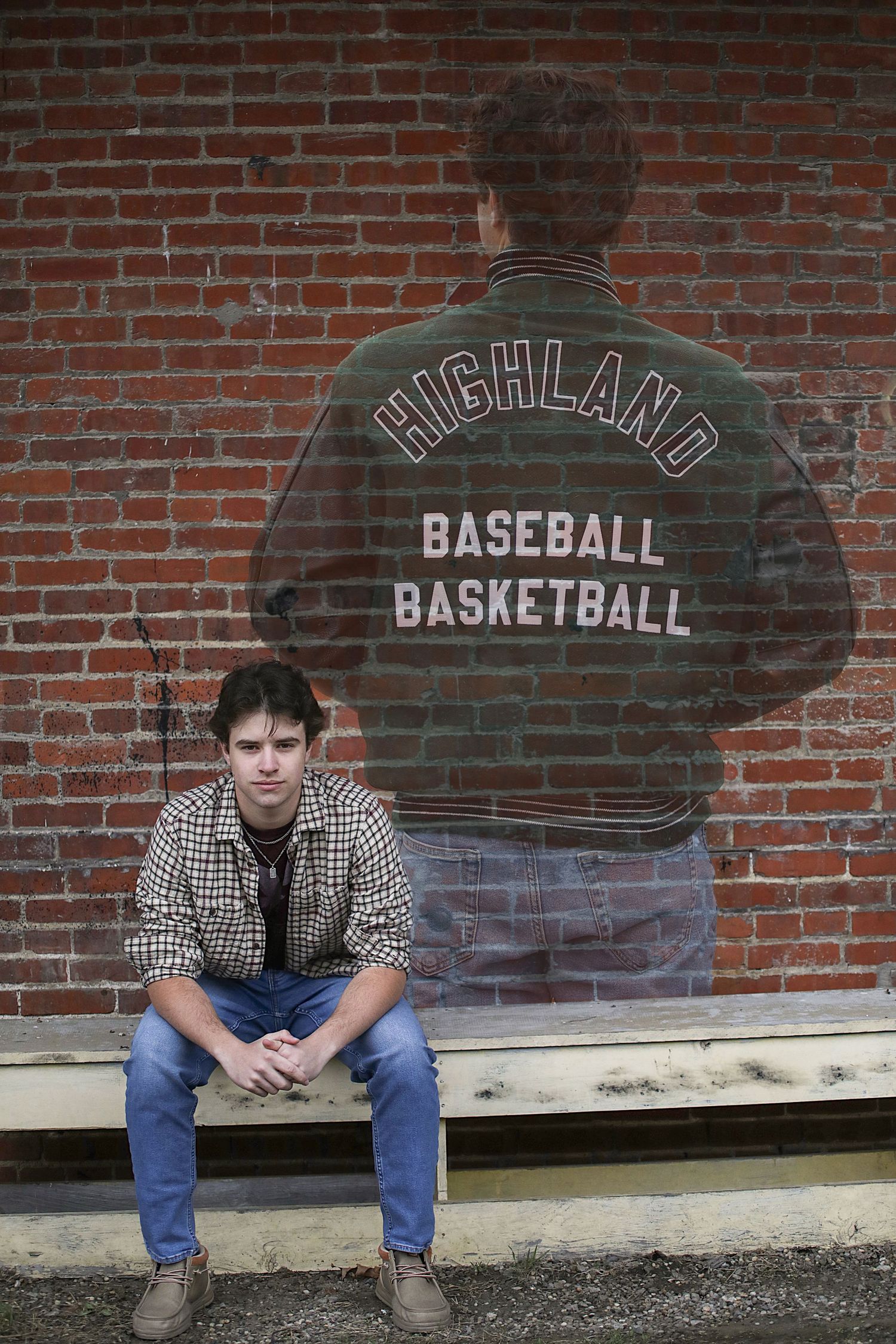 Person sitting against brick wall with Highland baseball and basketball letterman jacket shown behind them.