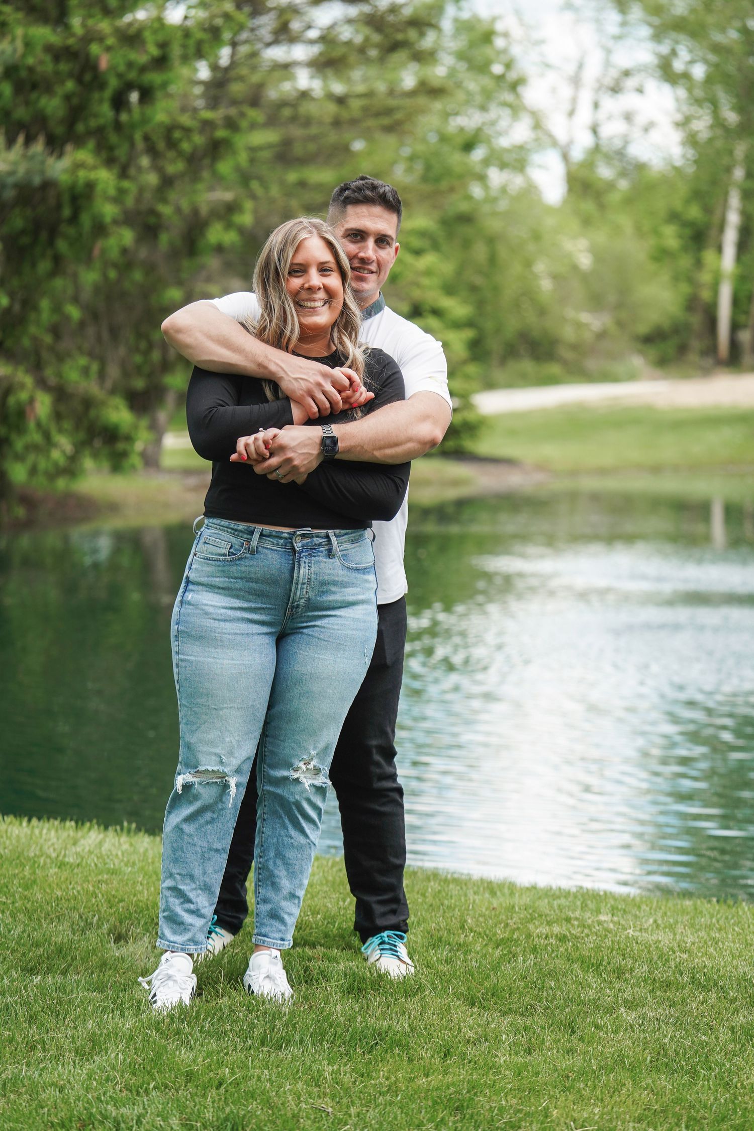 A couple shares intimate moments by a serene lake on a grassy shore in a romantic outdoor photoshoot sequence.