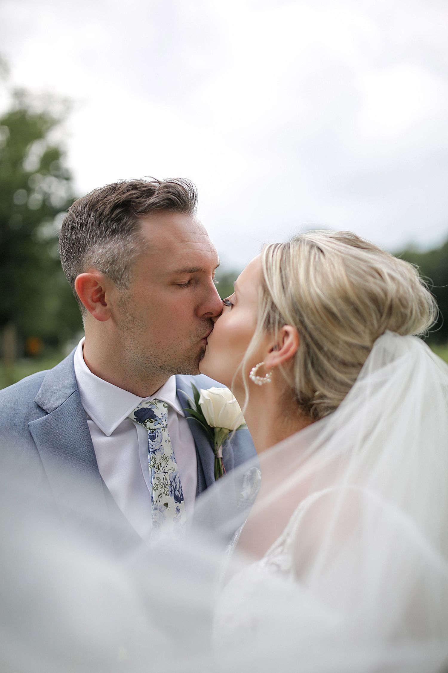 An intimate wedding kiss captured through a dreamy veil effect.
