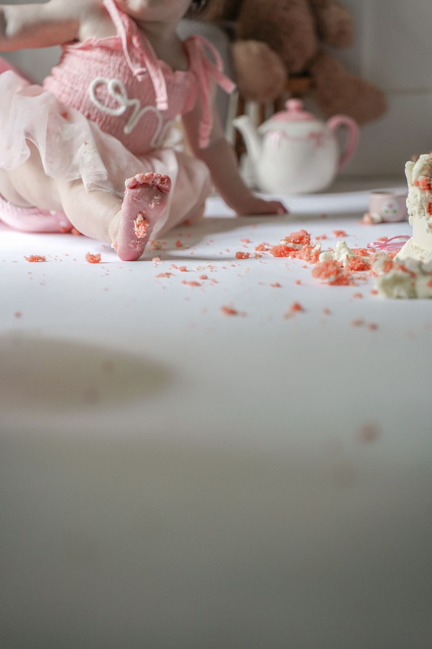 Pink and white decorative floral arrangement with scattered petals on a neutral grey surface.