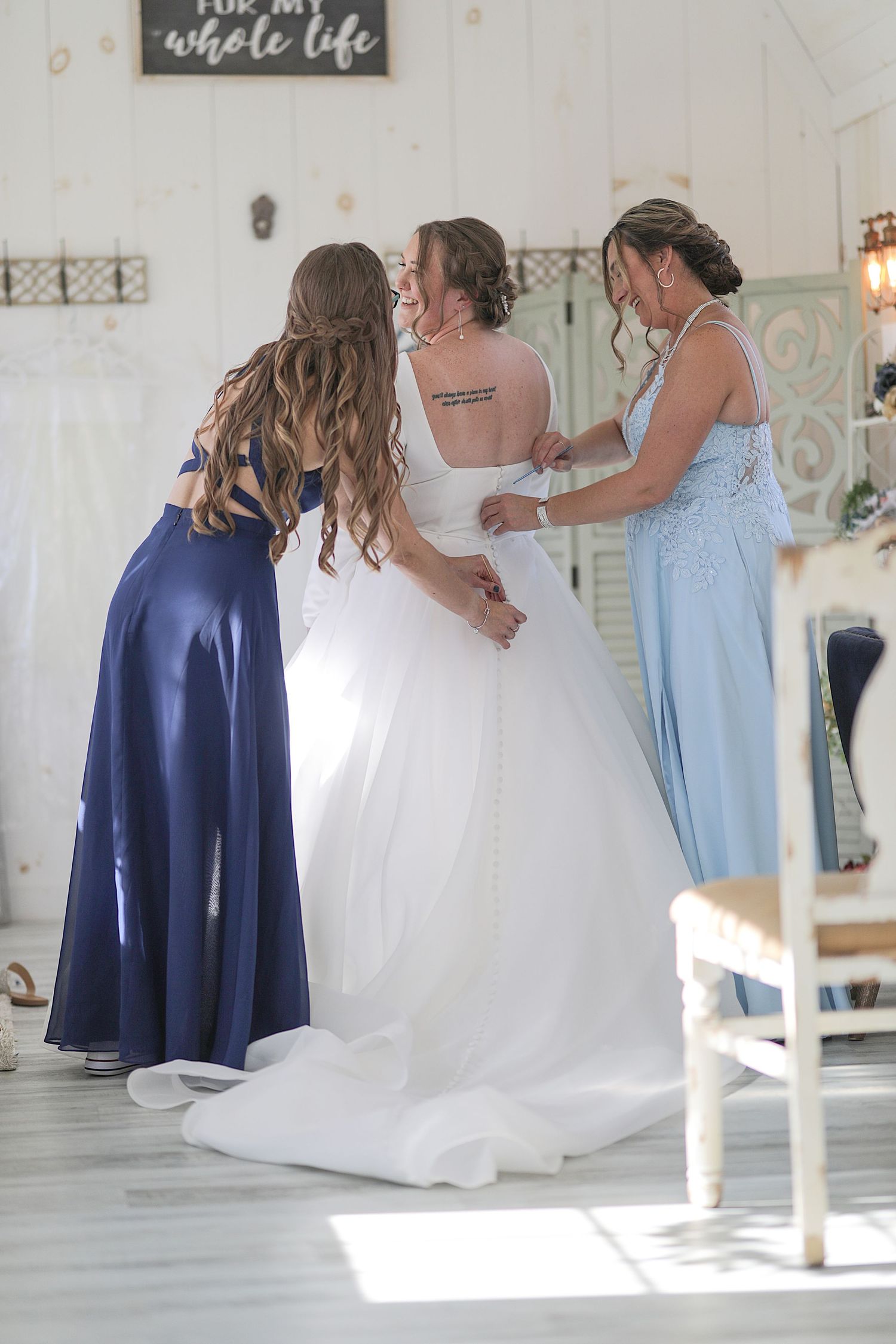 Bridal party poses in flowing gowns with navy blue and white dresses in an elegant indoor setting.
