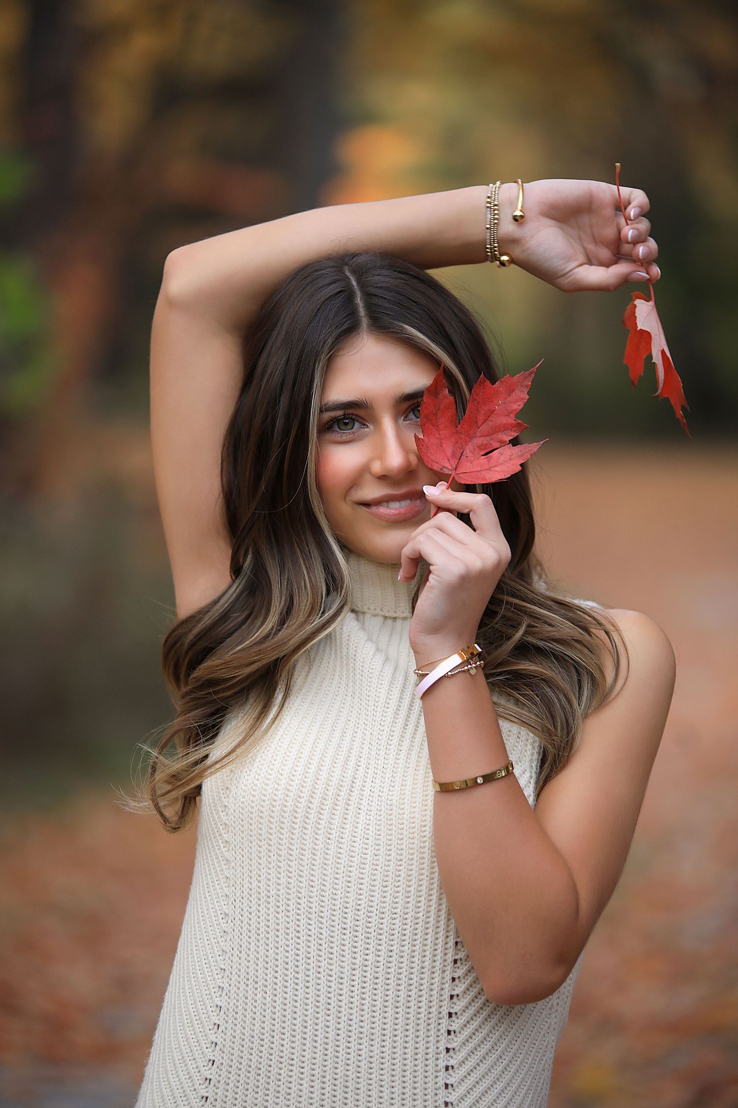 A white knit sweater photo sequence shows a bright red maple leaf being playfully held up against an autumn background.