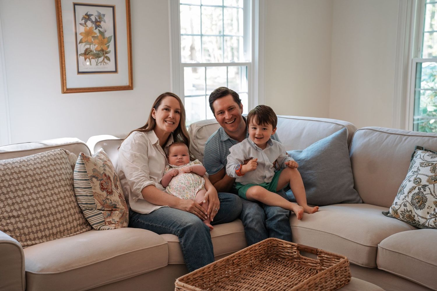 Family members relax together on a comfortable white couch in a bright living room with natural lighting.