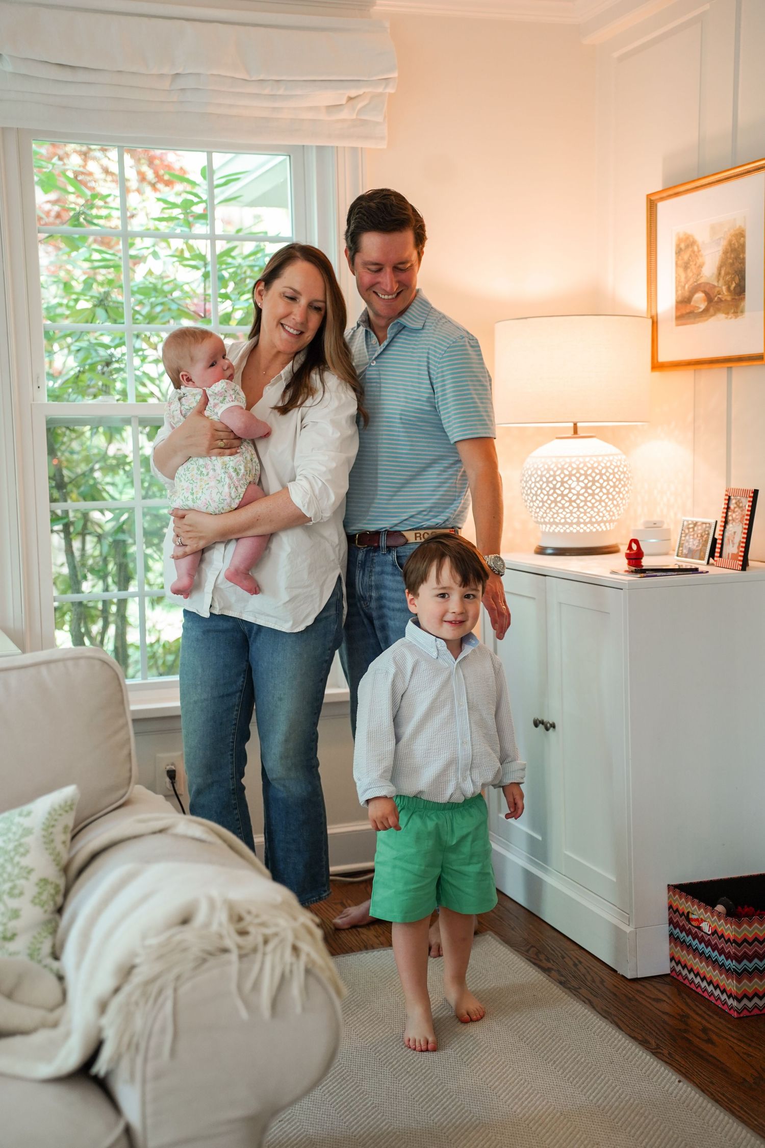 Family shares tender moments together on couch in sunlit living room during candid lifestyle photoshoot.