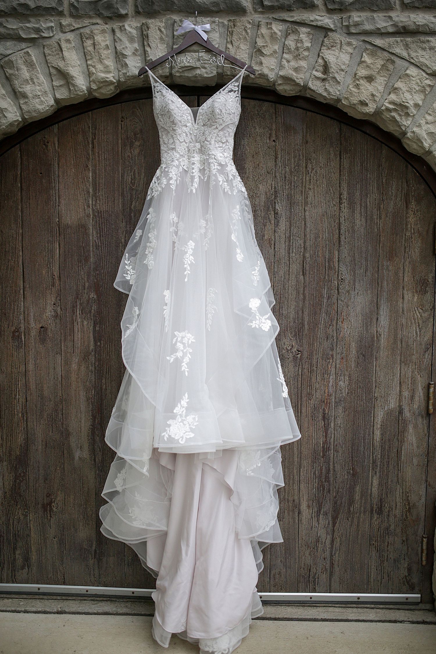 Lace and tulle wedding gown with sweetheart neckline displayed against dark wooden doors.