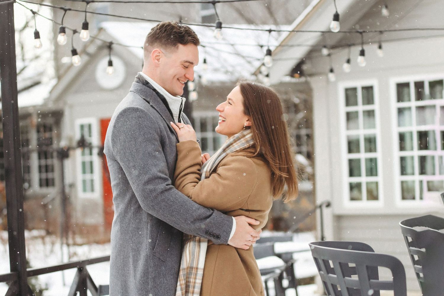 A couple dances together under string lights in a covered outdoor venue during a romantic moment.