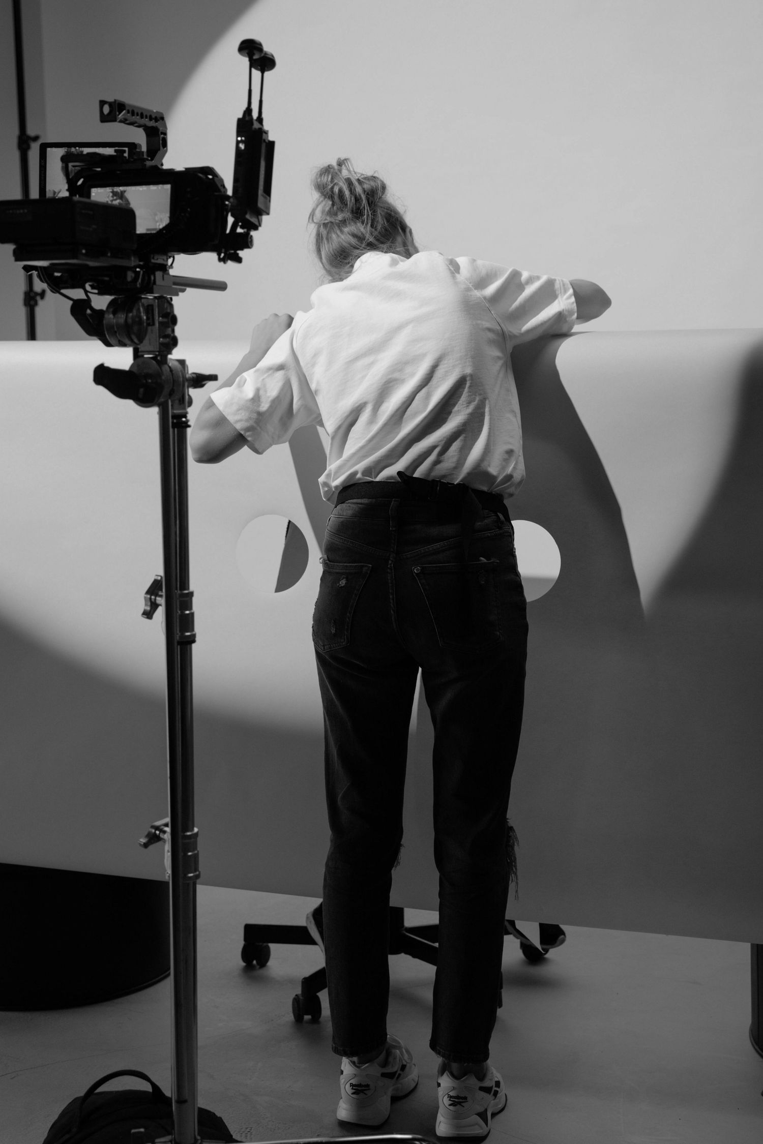 Behind-the-scenes black and white photo of someone operating a professional camera setup in a studio environment.