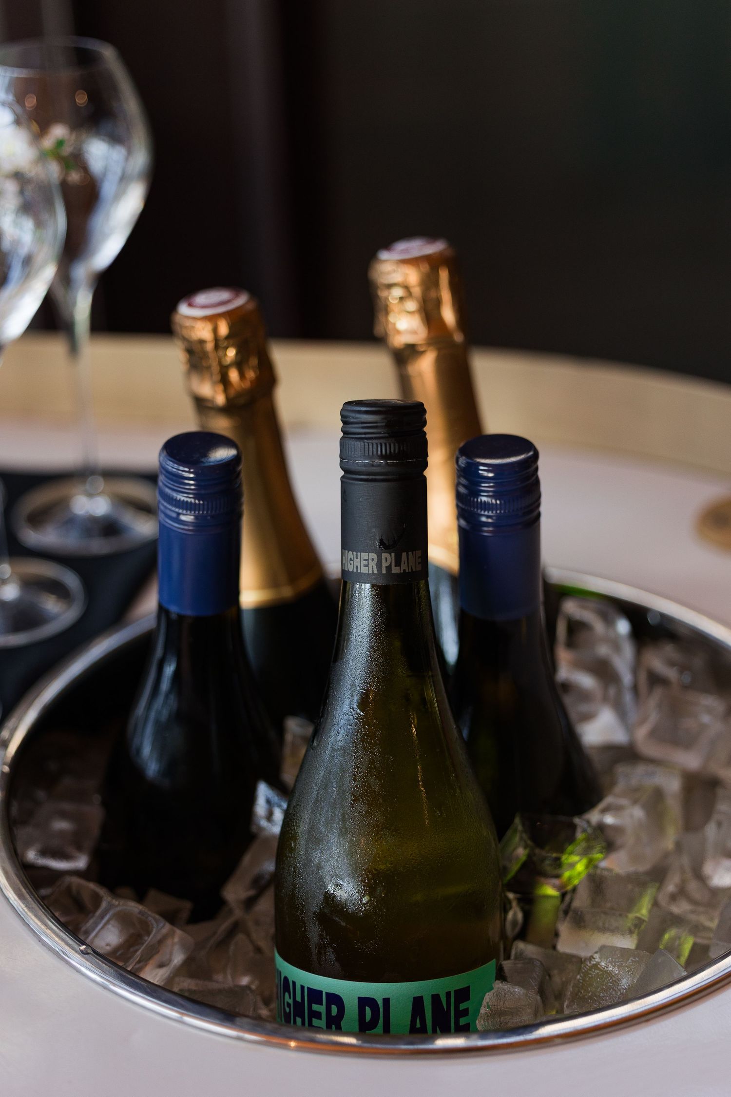 Bottles of Higher Plane wine chilling in an ice bucket on a silver tray at an elegant event.