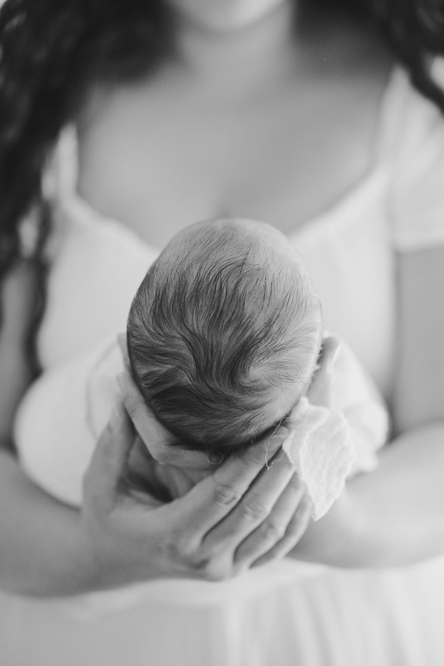 A series of black and white photographs showing a sleeping newborn baby cradled in gentle hands.