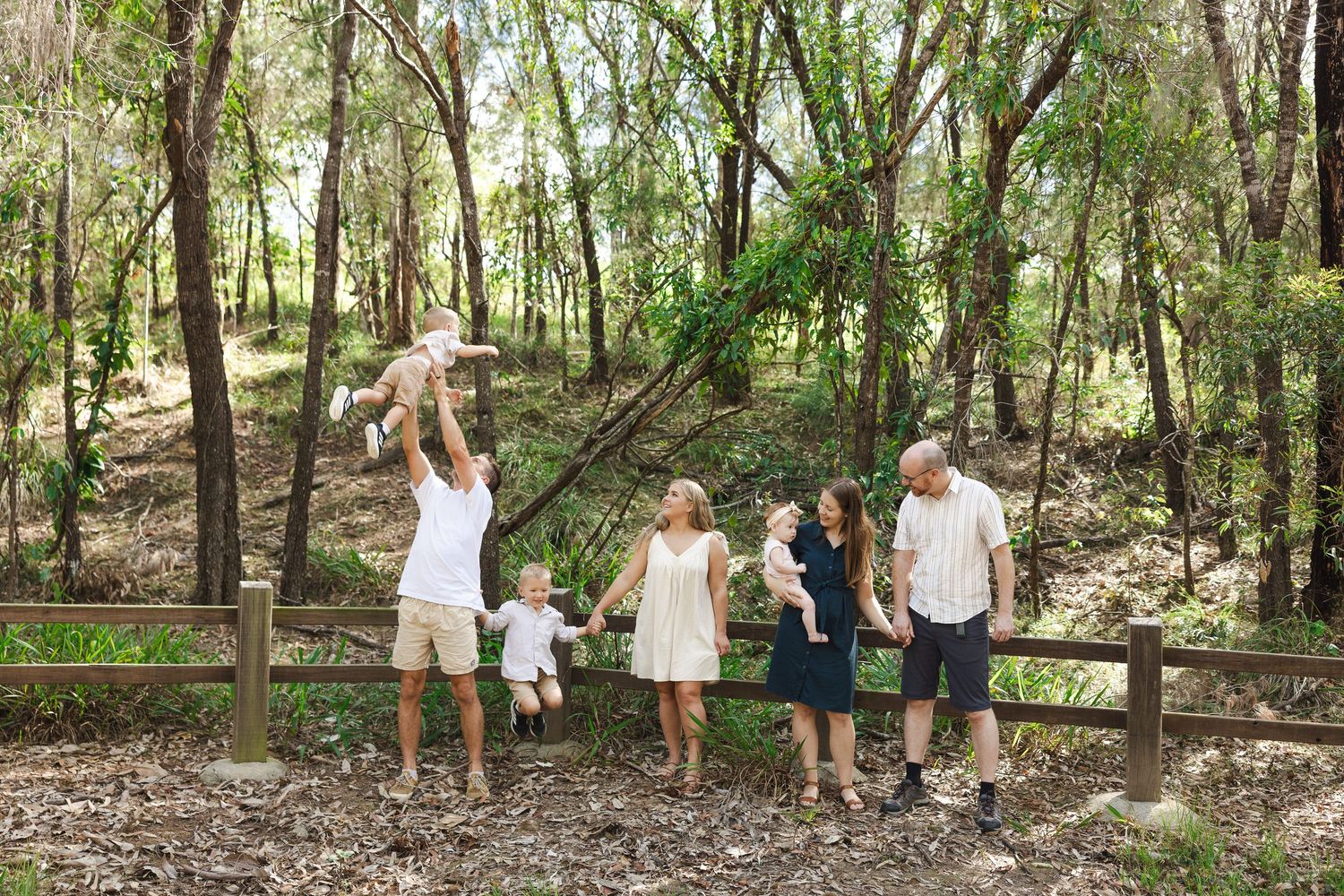 A group of people walk together through a lush wooded forest trail on a sunny day.