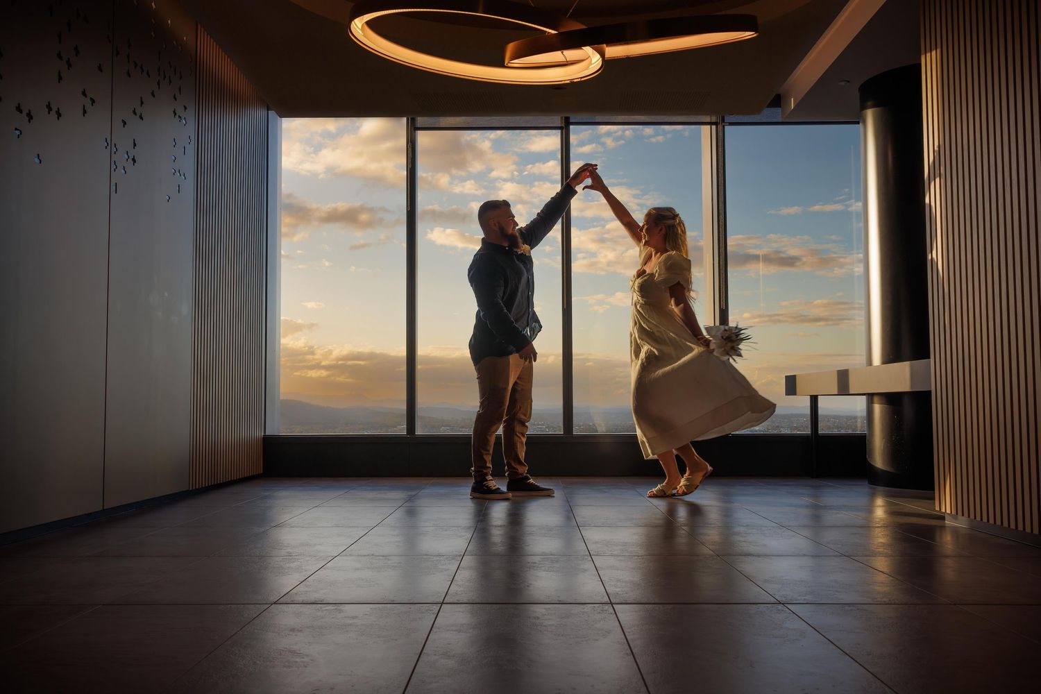 Silhouettes dance against a sunset window in an modern indoor setting.