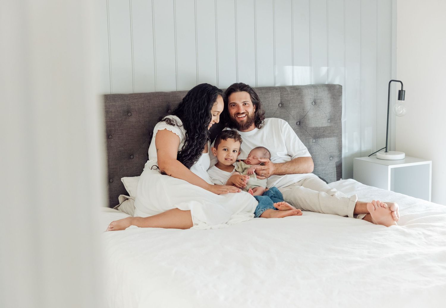 Family spending quality time together while relaxing on white bed in bright bedroom.