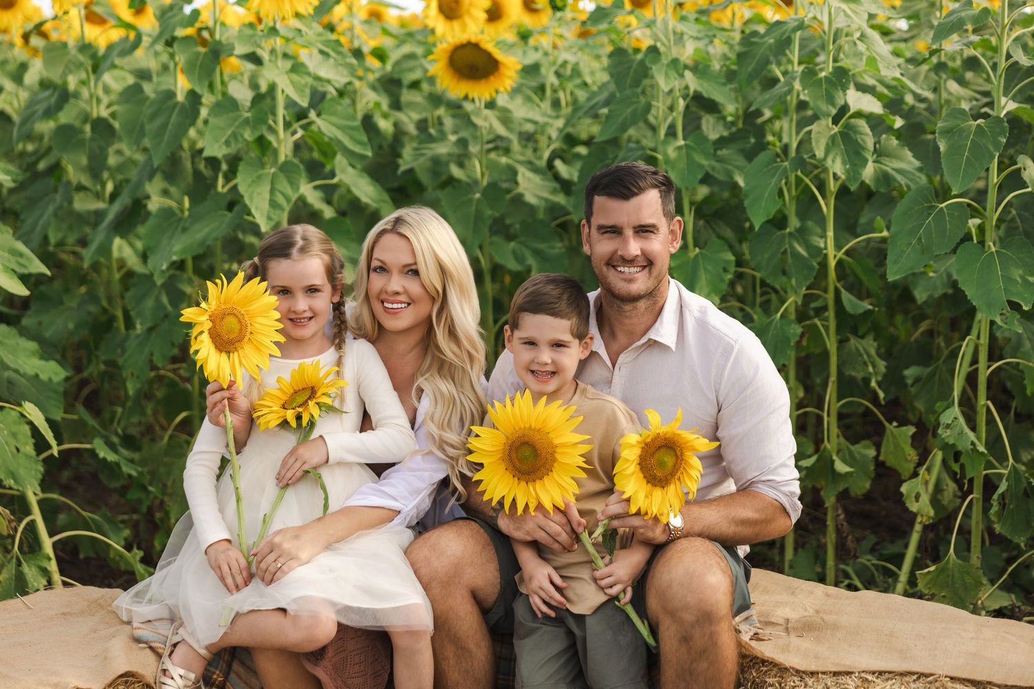 A family poses together in a vibrant sunflower field during a summer photo session.