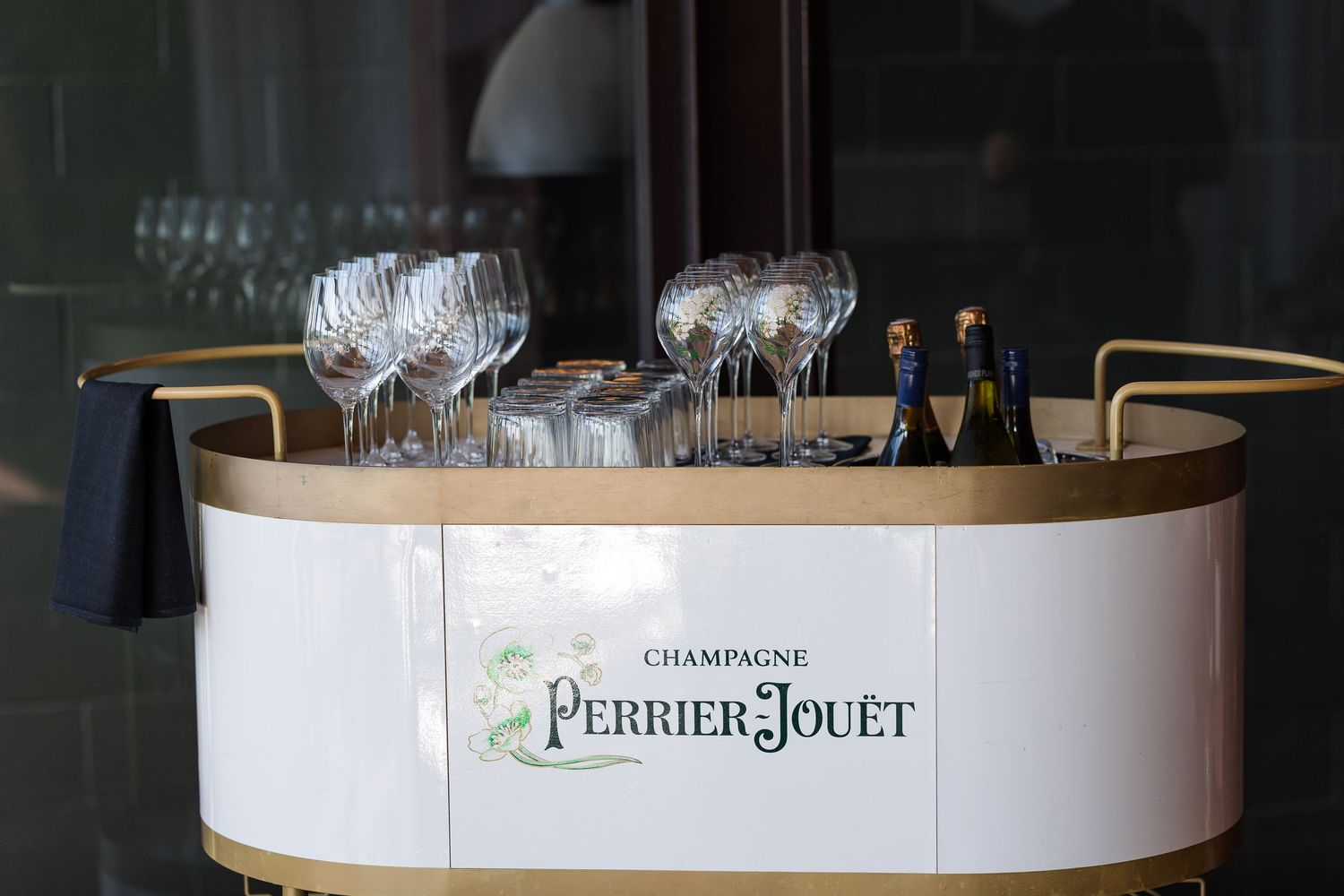 Perrier-Jouët Champagne bar display with elegant crystal glasses and bottles on a gold and white curved counter.