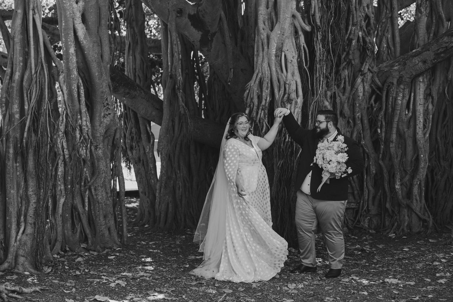 Black and white wedding photos showing couples and wedding party members posing under trees in a romantic outdoor setting.