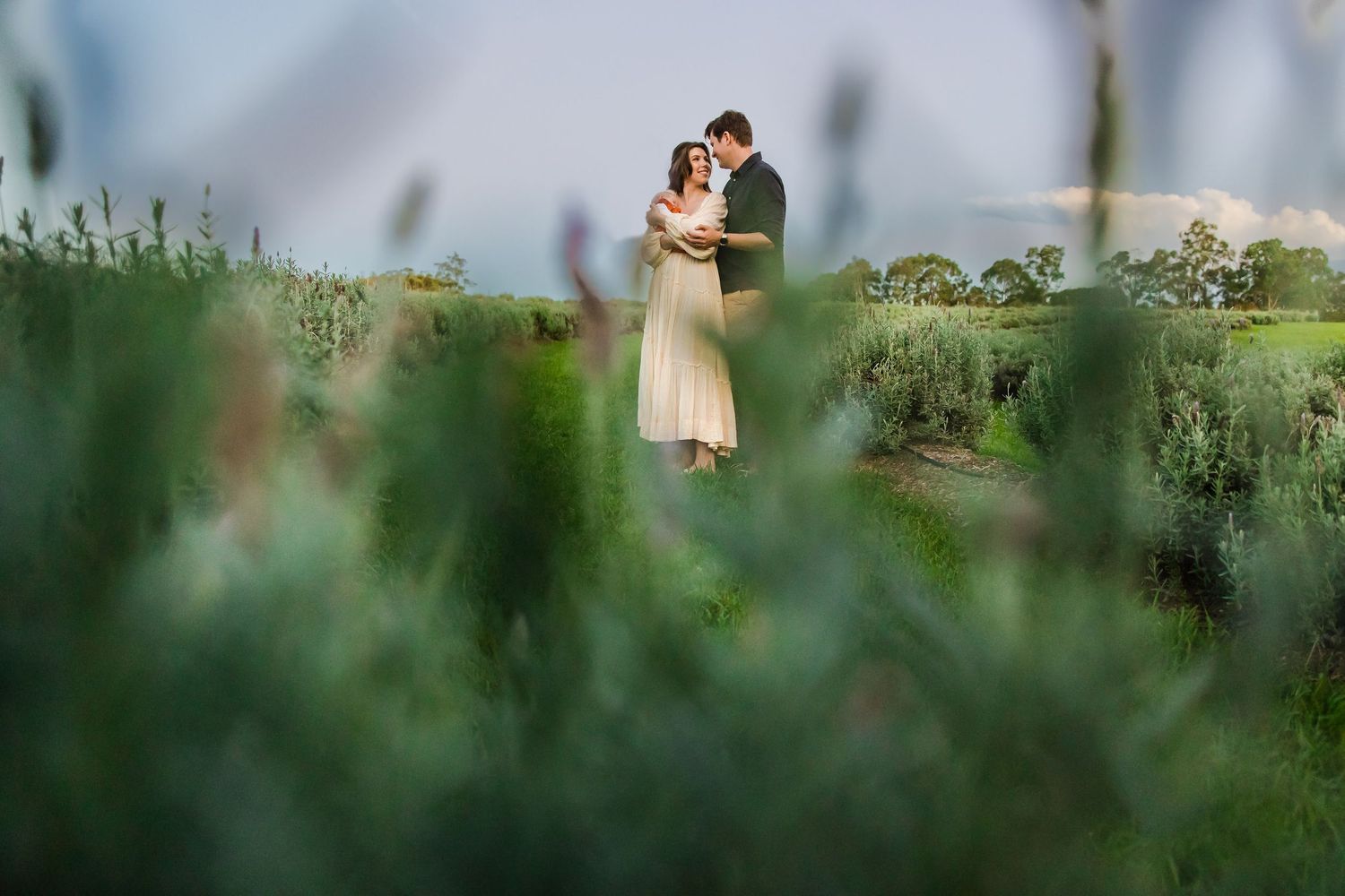 Couple embracing in lush green garden field at dusk, romantic outdoor wedding portrait photography.