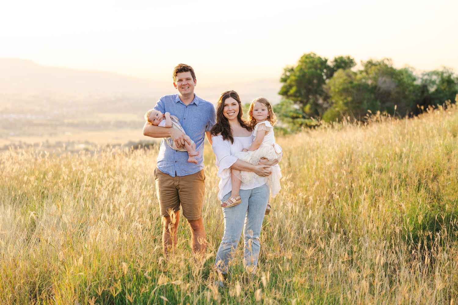 People enjoying a sunset walk in a golden meadow with tall grass on a sloping hillside.