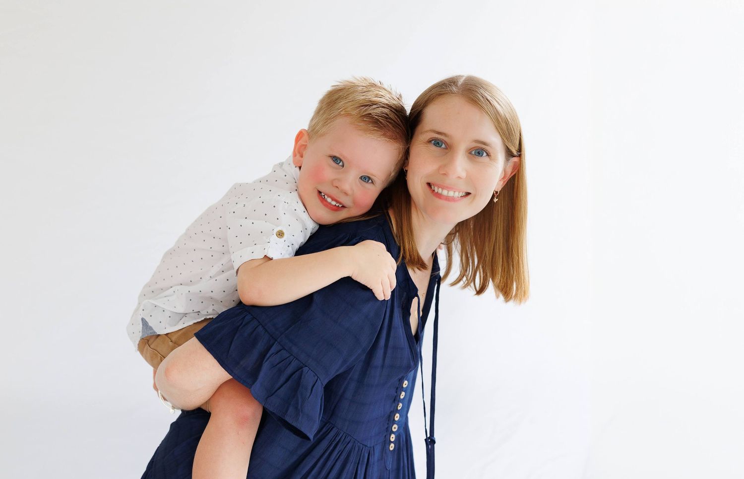Sweet outdoor family portrait showing mother and child wearing matching navy blue outfits and smiling together.