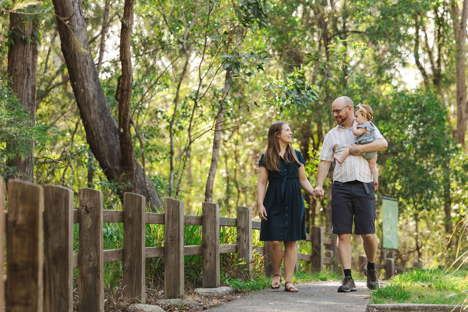 People walking and jogging along a tree-lined path in a serene park setting during daytime.