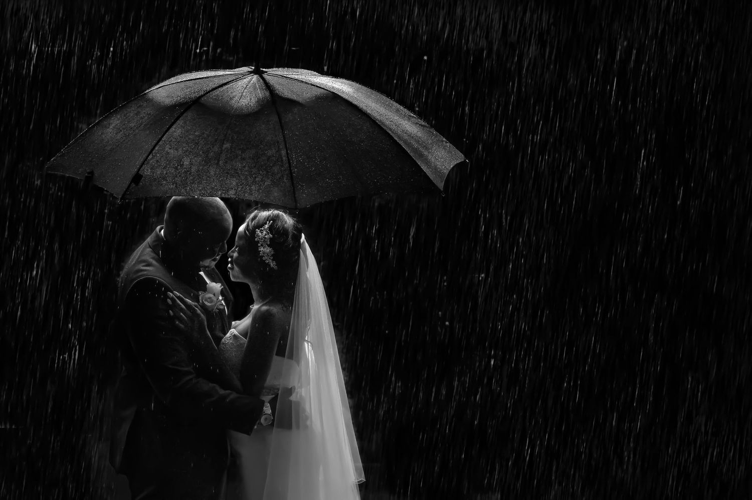 Romantic silhouette of couple sharing intimate moment under umbrella in the rain.