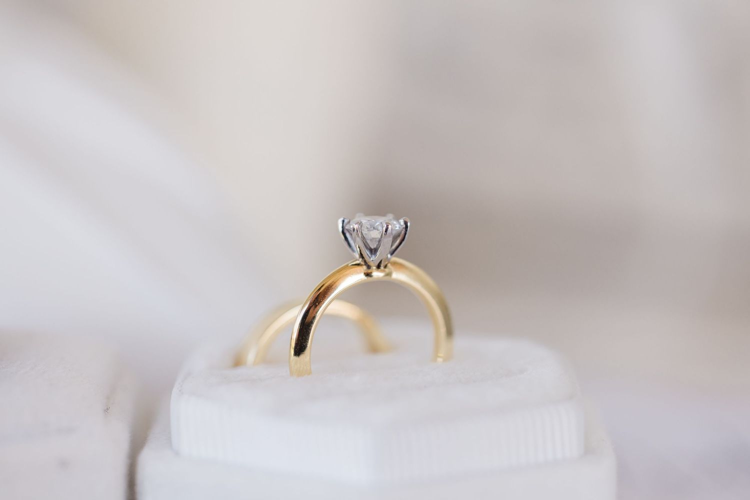 Yellow gold solitaire engagement ring with round diamond in silver prong setting displayed in white ring box.