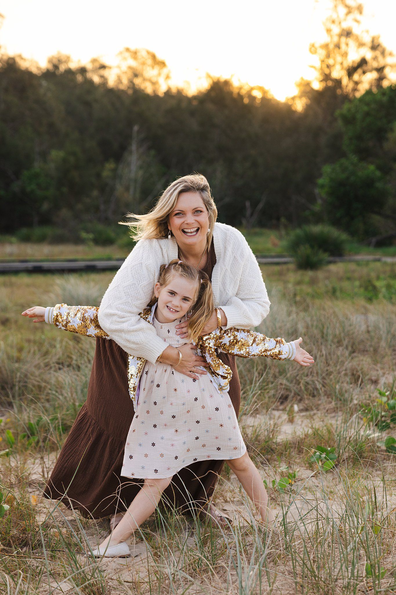 A heartwarming family moment captured outdoors in a field at sunset with warm lighting and natural surroundings.