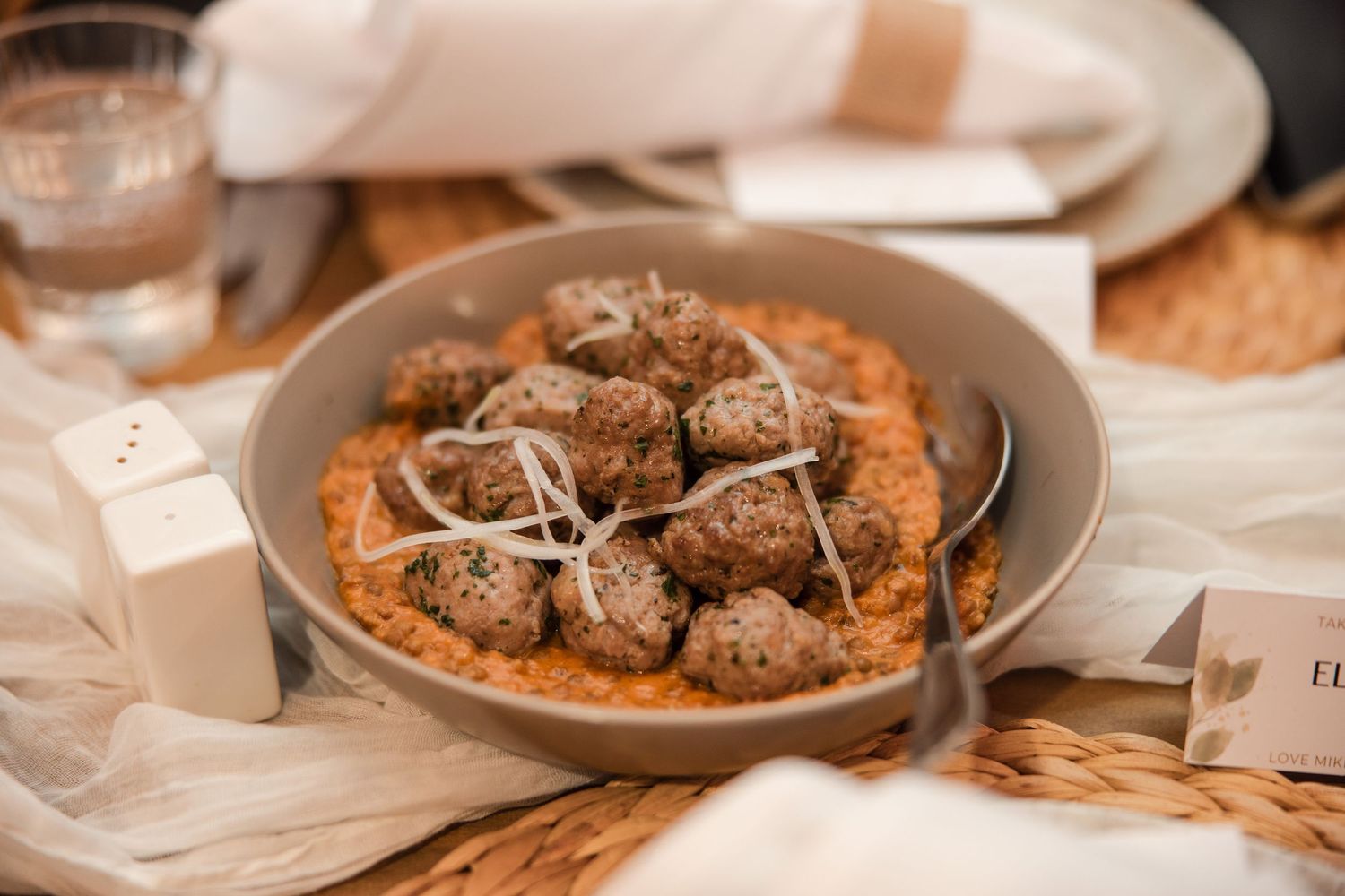 Savory meatballs served on a bed of tomato sauce in a gray bowl, elegantly presented on a woven placemat.