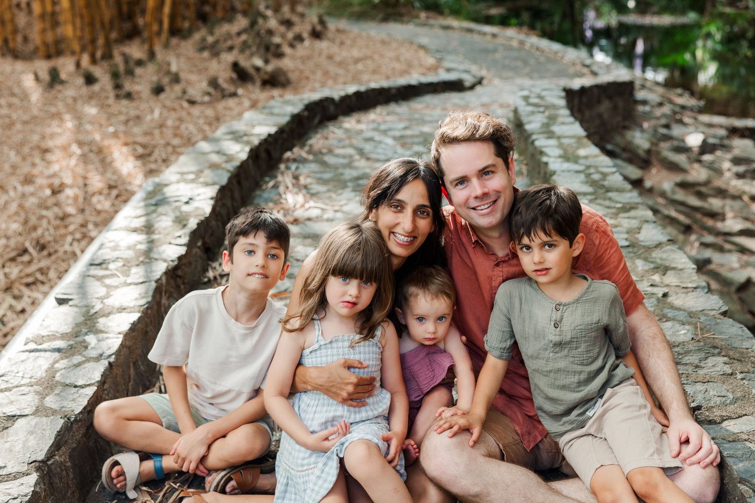 A family sits together on stone steps outdoors during a casual photo session.