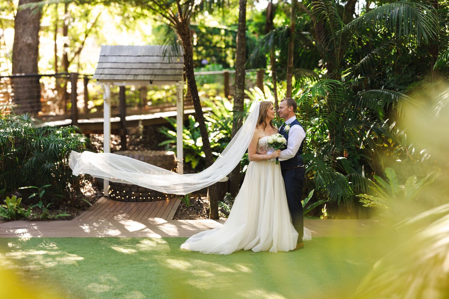 Panoramic view of a garden wedding venue with tropical foliage and white decorative elements.