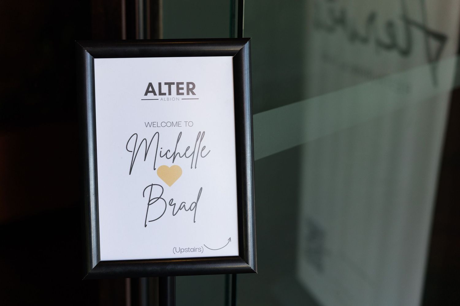 A framed welcome sign at Alter restaurant reads Welcome to Michelle and Brad with a gold heart accent.