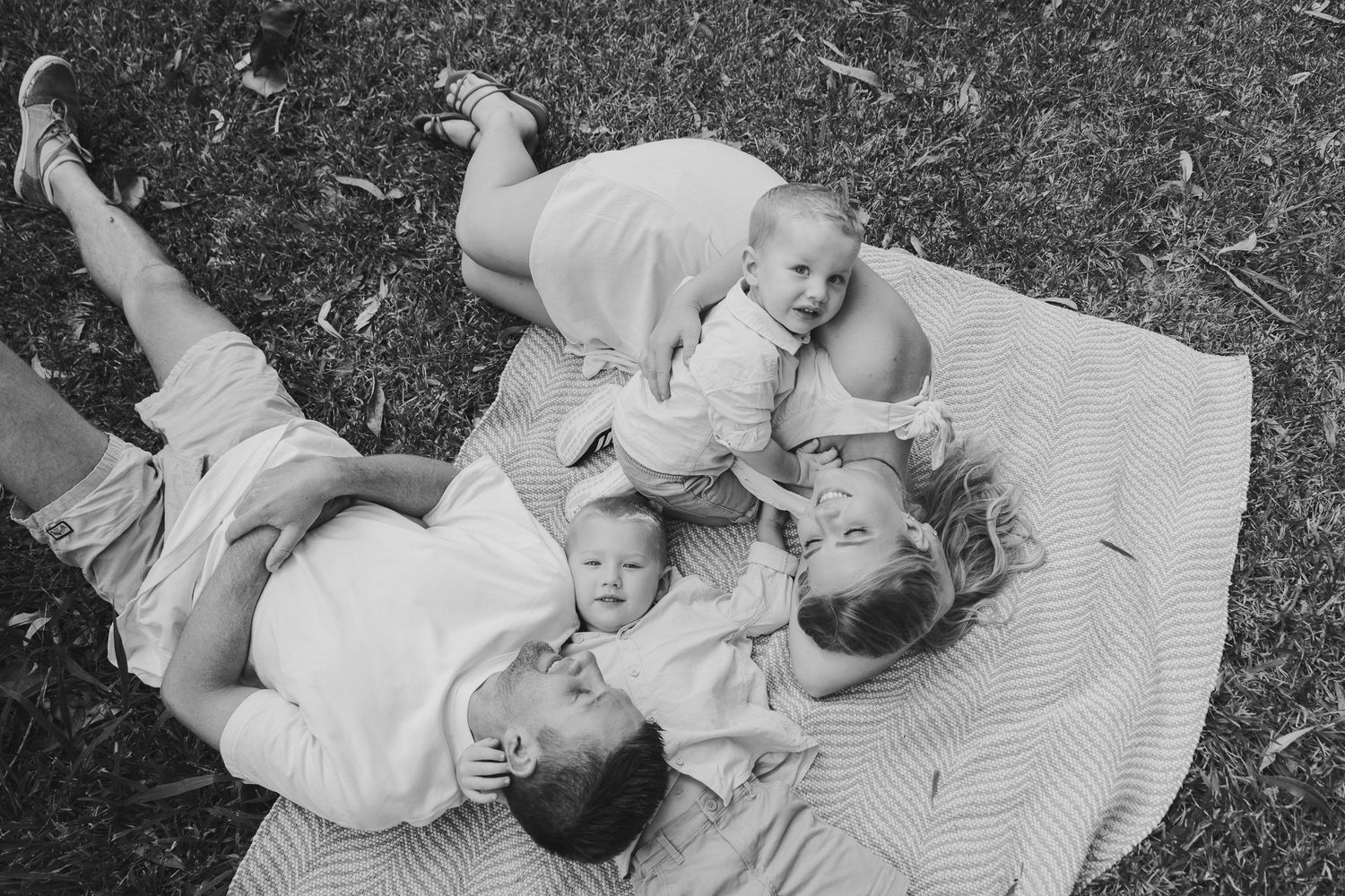 A series of black and white photographs showing a baby lying on a blanket outdoors in various poses.