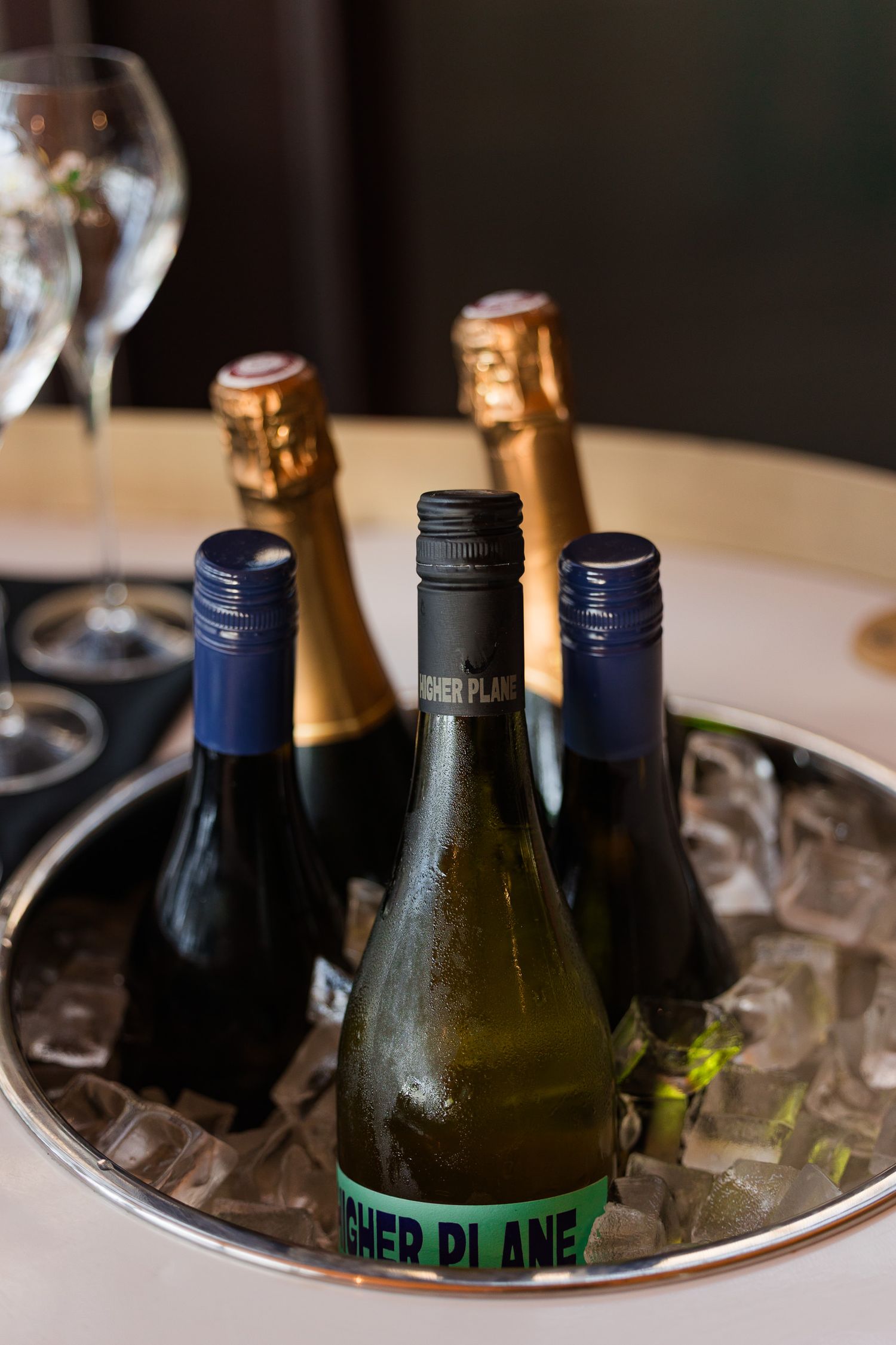 Assorted wine and champagne bottles chilling in an ice bucket on a silver tray at an elegant dining event.