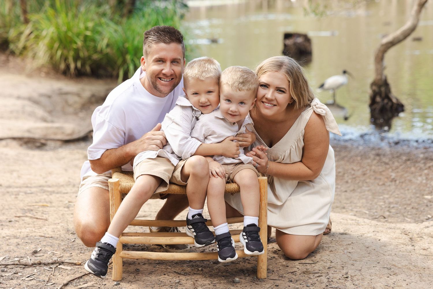 Family sitting together and playing near a stream on a sunny day in nature.