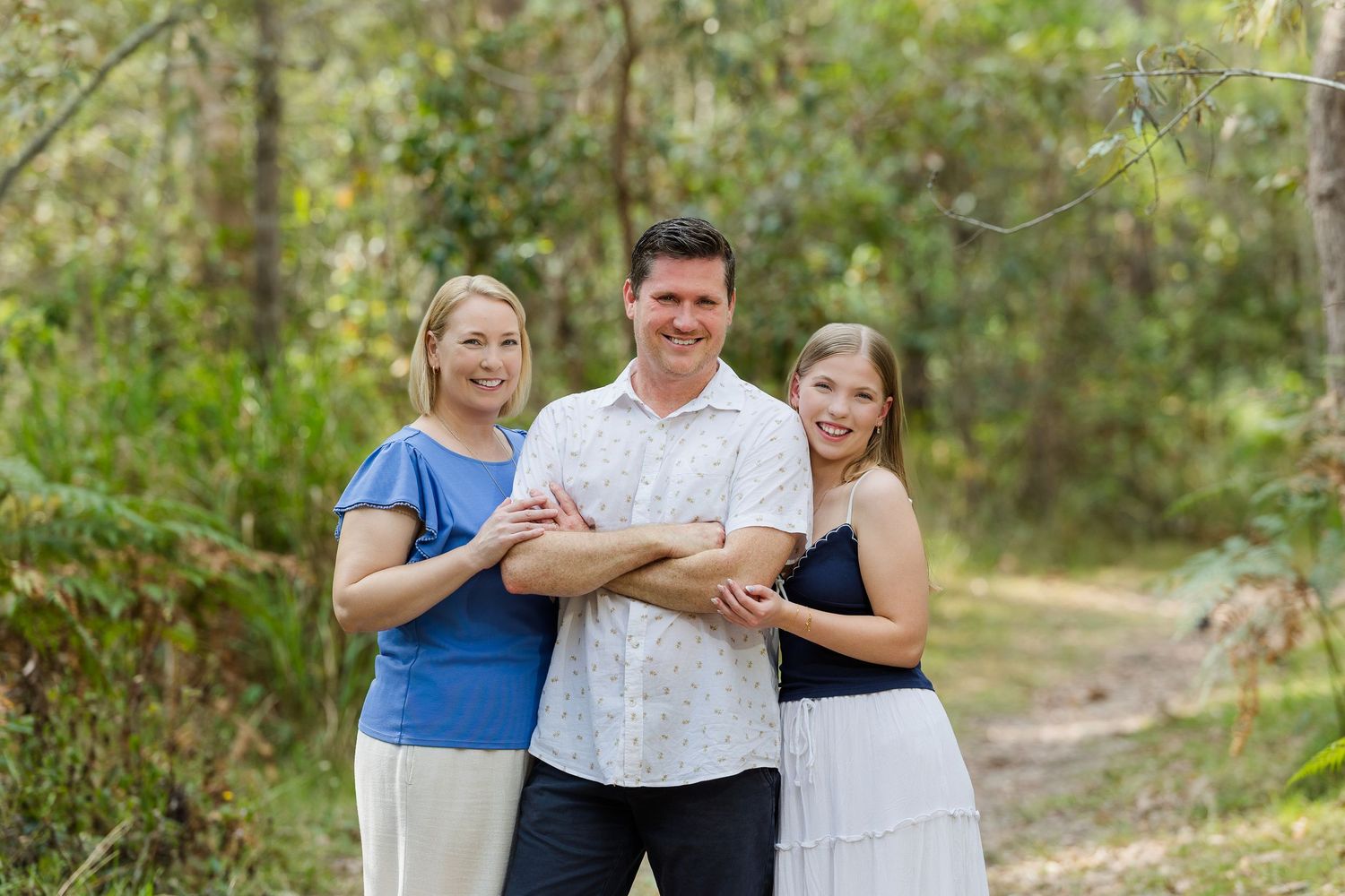 A family shares joyful moments together while posing outdoors in coordinated blue and white outfits.
