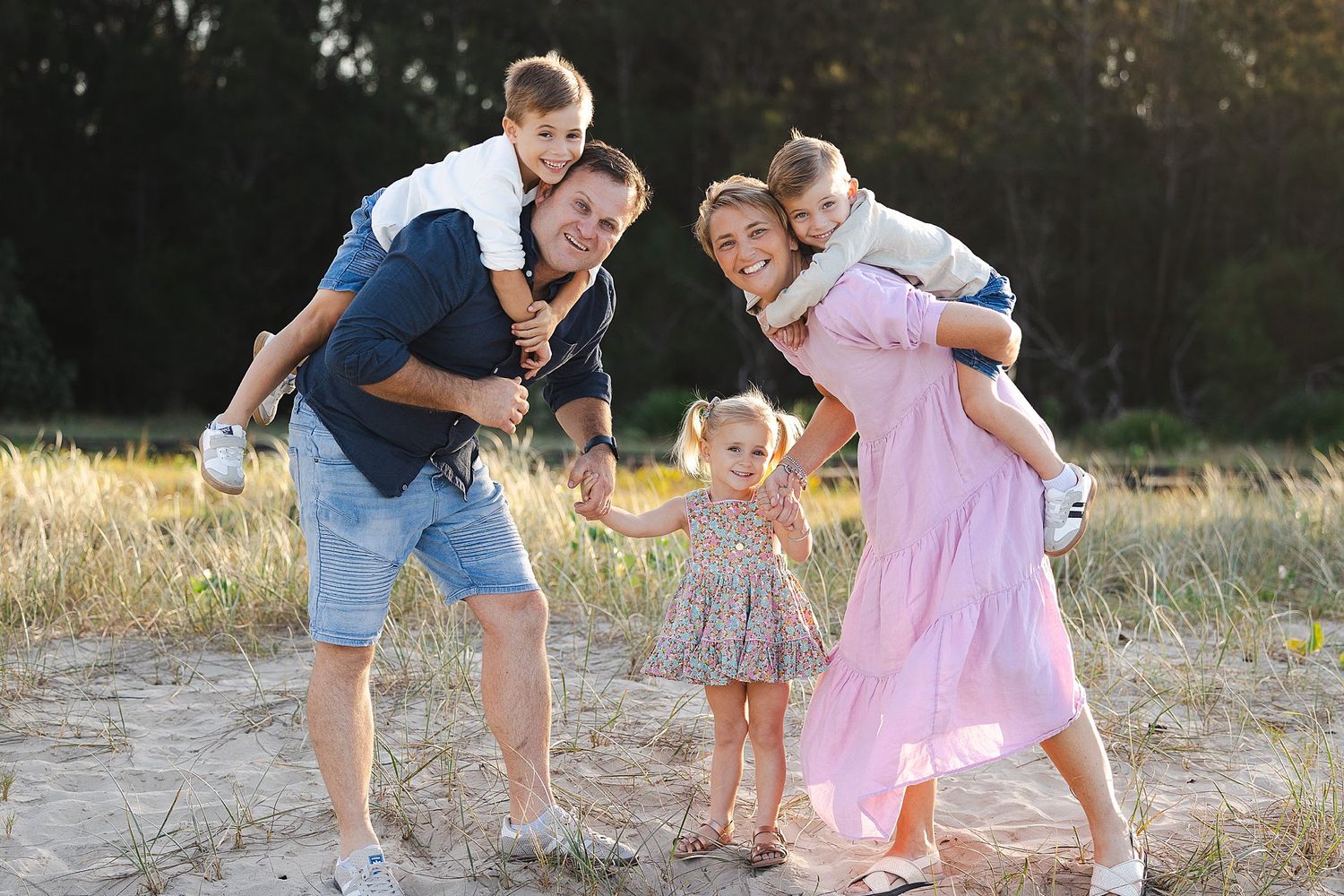 A happy family plays together in a sunny field at golden hour, creating joyful moments in the warm evening light.