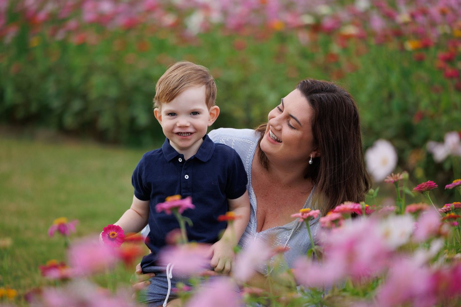 Two people enjoying a sunny day together among blooming pink cosmos flowers in a garden setting.