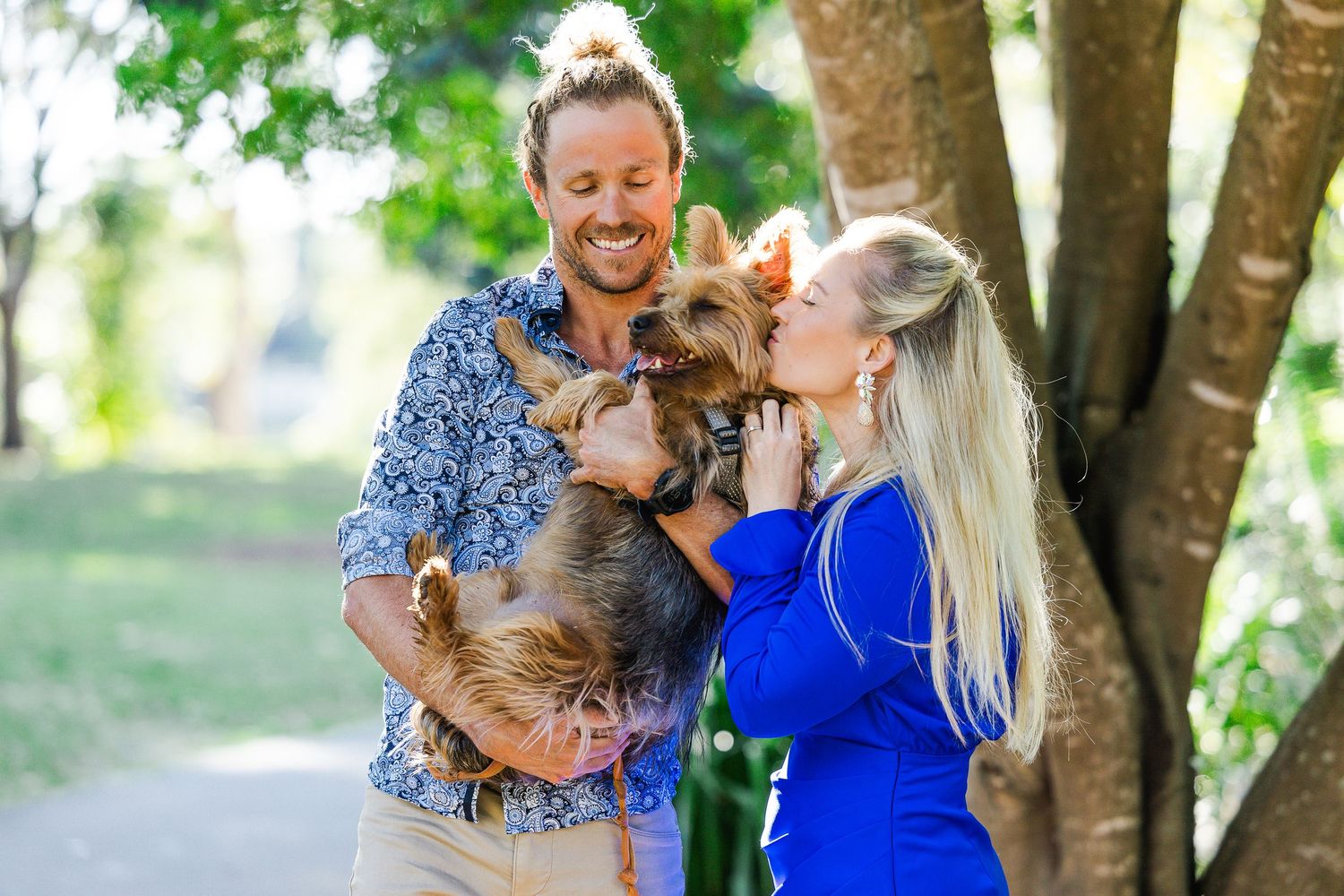 Family enjoying a fun summer photoshoot together in a park with trees and natural lighting.